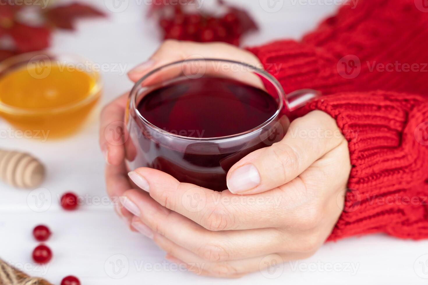 Women's hands hold a mug with hot viburnum tea. Seasonal vitamin drink. Close-up. Selective focus. photo