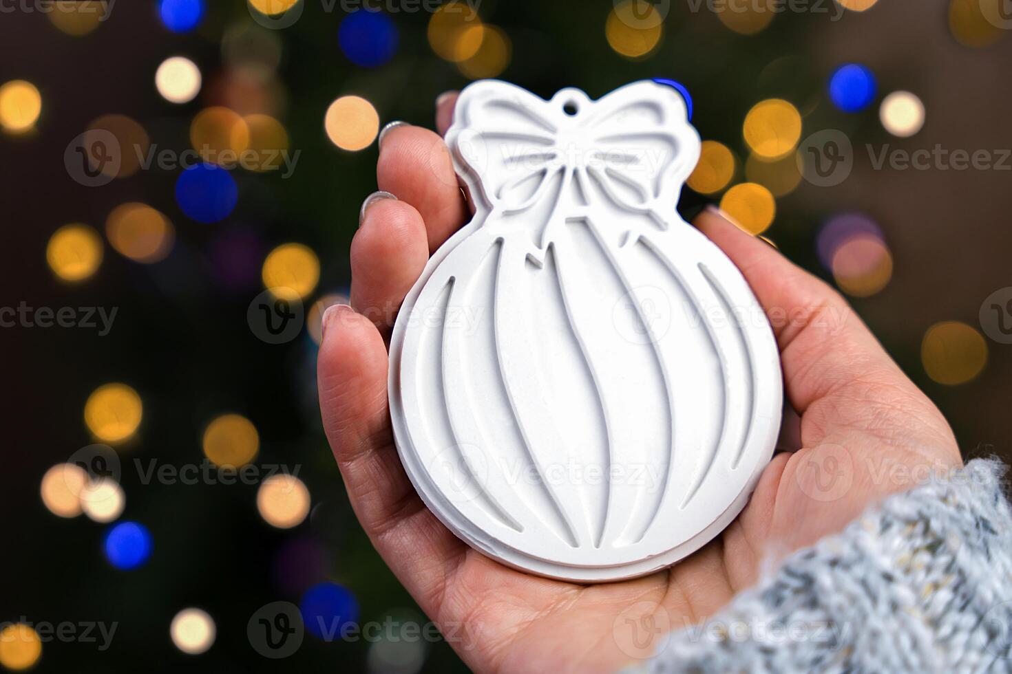 A woman's hand holds a handmade Christmas tree toy from gypsum. DIY gifts. Christmas tree decoration. Close-up. Selective focus. photo