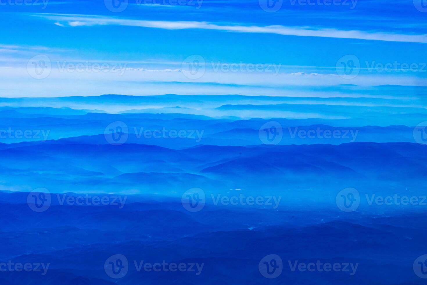 Aerial view from airplane window above green ground. View from the airplane window with beautiful clouds at sunrise. Earth and sky as seen through window of an airplane. photo