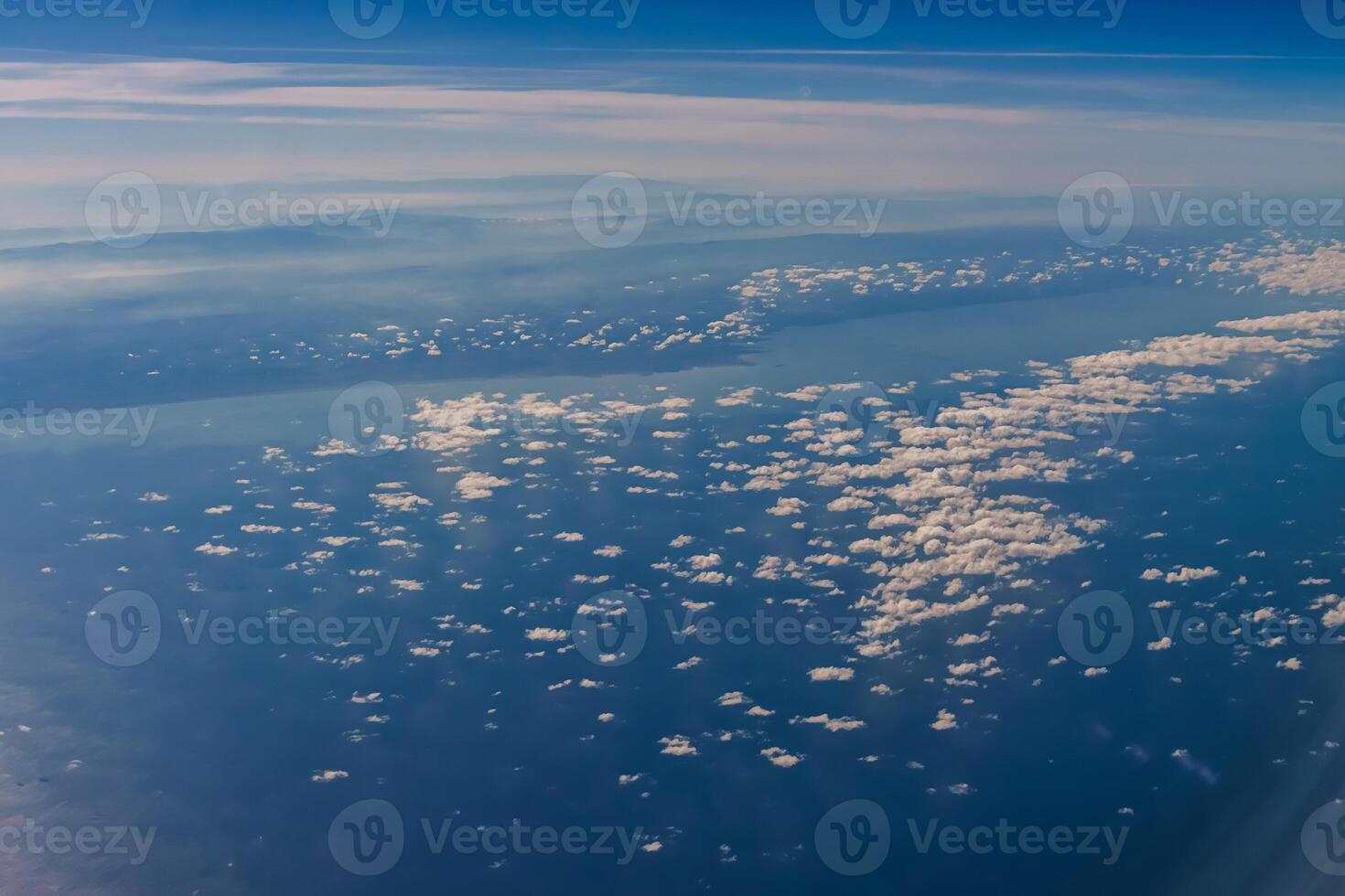 Aerial view from airplane window above green ground. View from the airplane window with beautiful clouds at sunrise. Earth and sky as seen through window of an airplane. photo