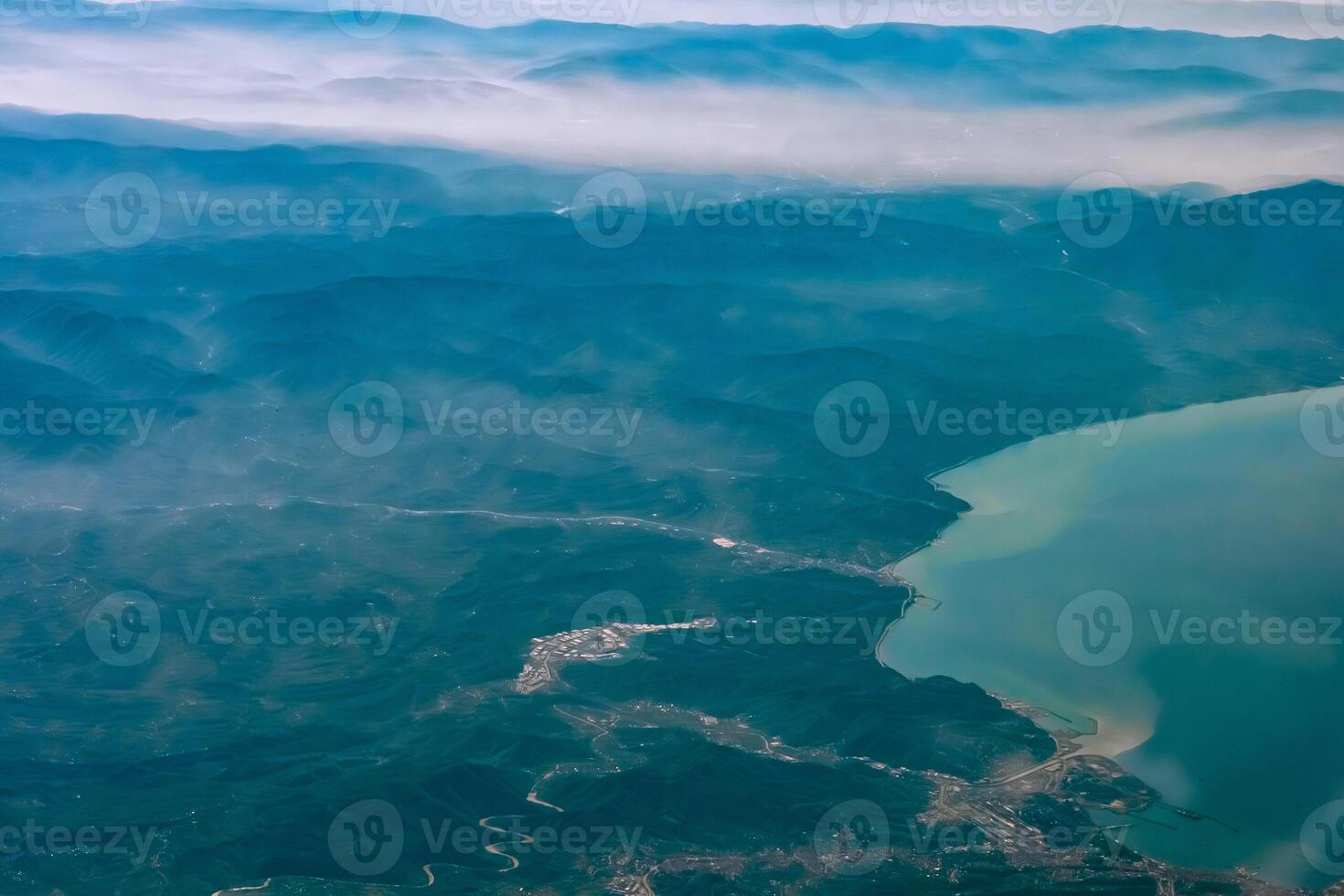 Aerial view from airplane window above green ground. View from the airplane window with beautiful clouds at sunrise. Earth and sky as seen through window of an airplane. photo