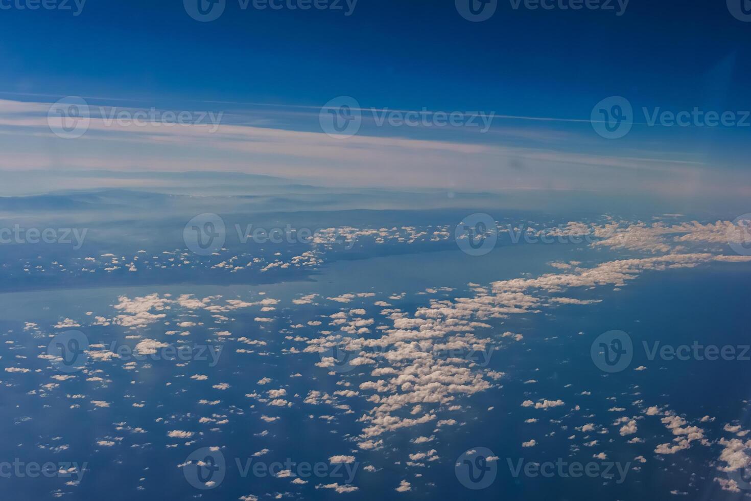 Aerial view from airplane window above green ground. View from the airplane window with beautiful clouds at sunrise. Earth and sky as seen through window of an airplane. photo