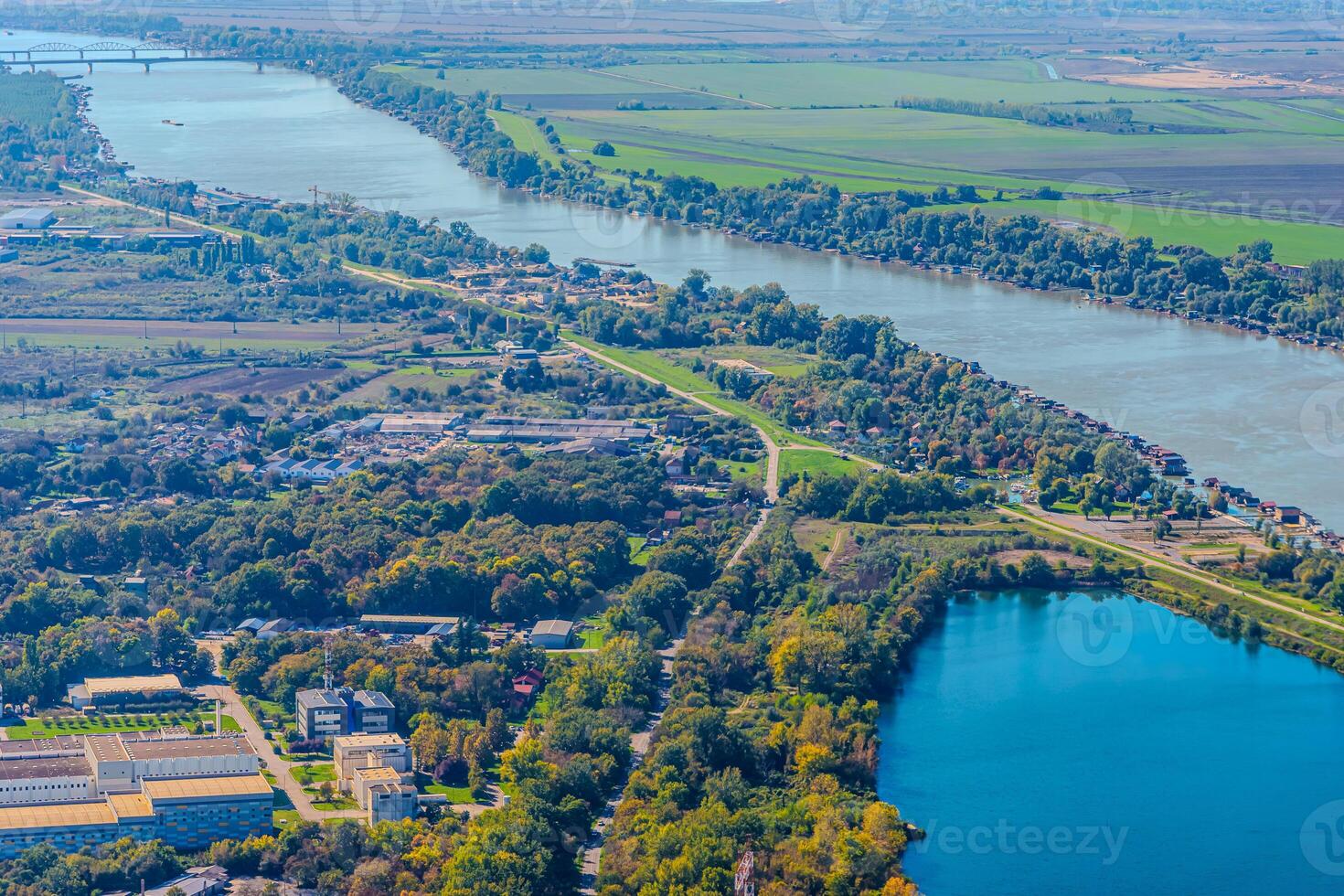 Aerial view of valley with farm fields, pond and Danube river. High quality photo