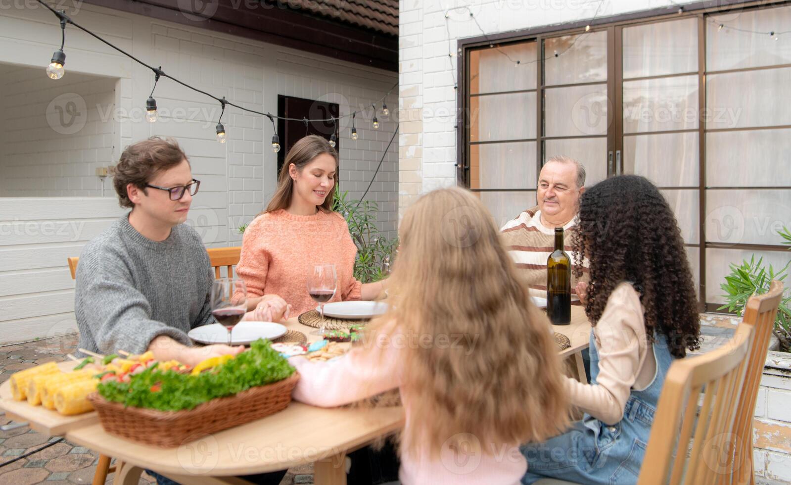 Grandfather, parents, and the teenage girls are all having dinner together at home photo