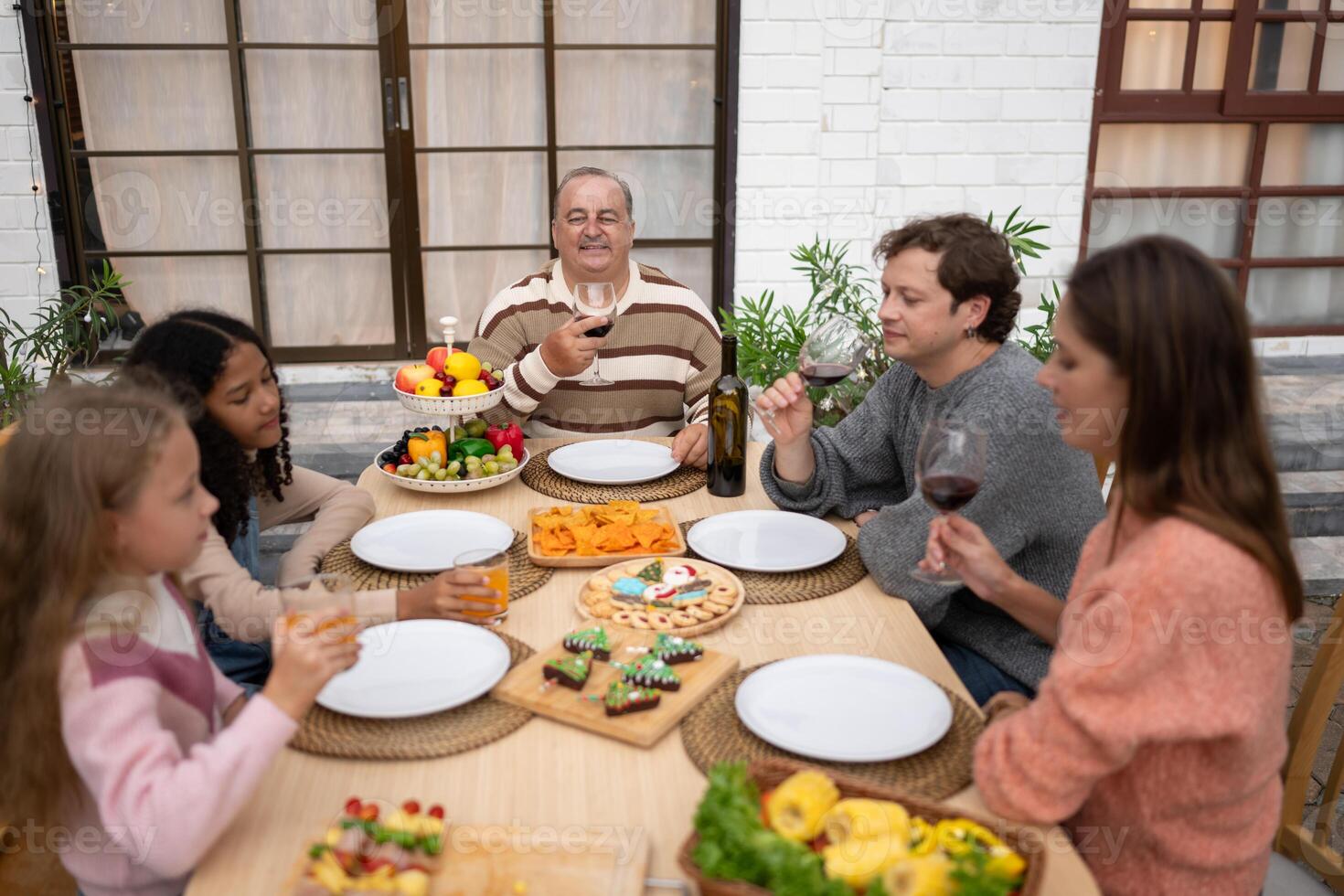 Grandfather, parents, and the teenage girls are all having dinner together at home photo