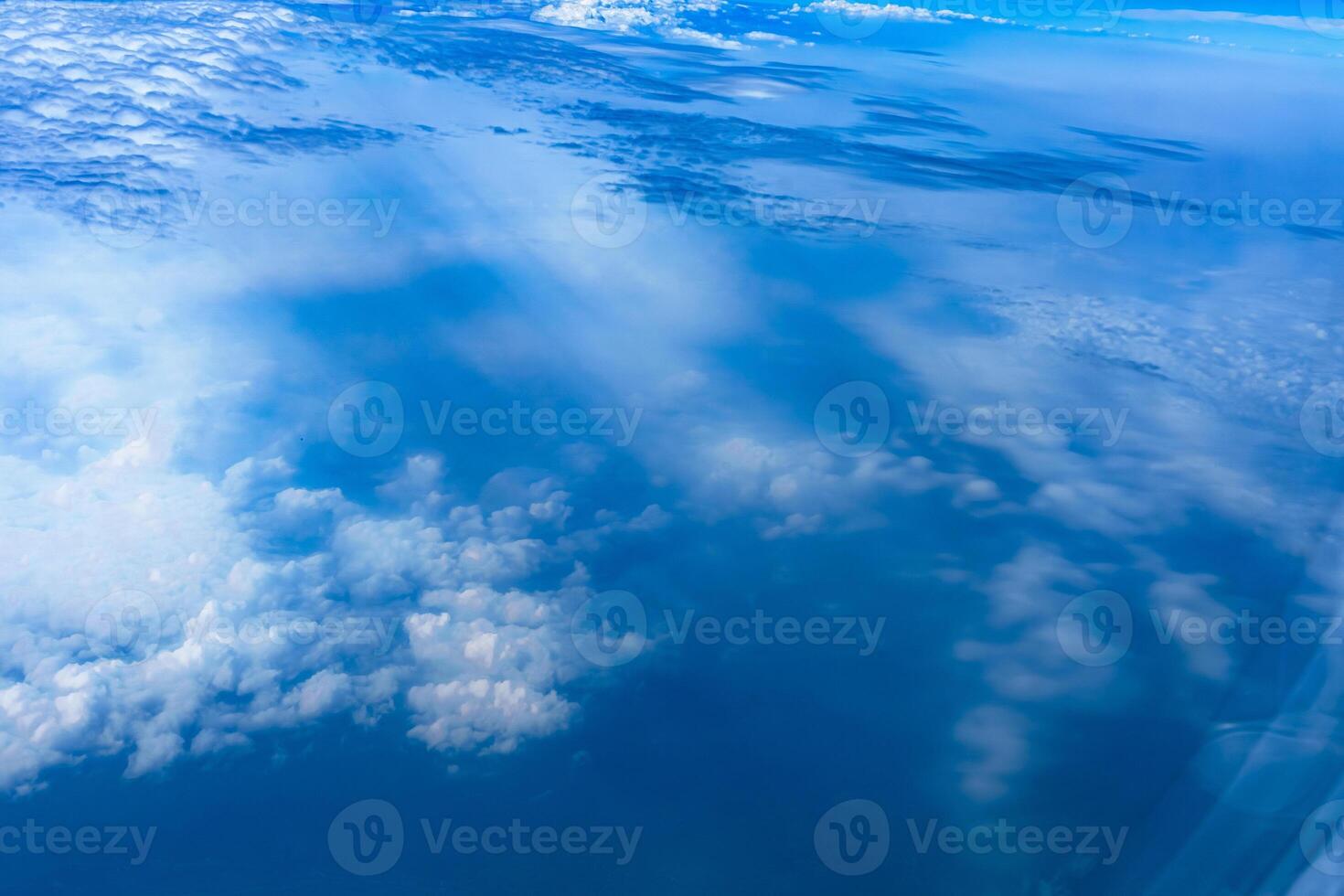 Aerial view from airplane window above green ground. View from the airplane window with beautiful clouds at sunrise. Earth and sky as seen through window of an airplane. photo