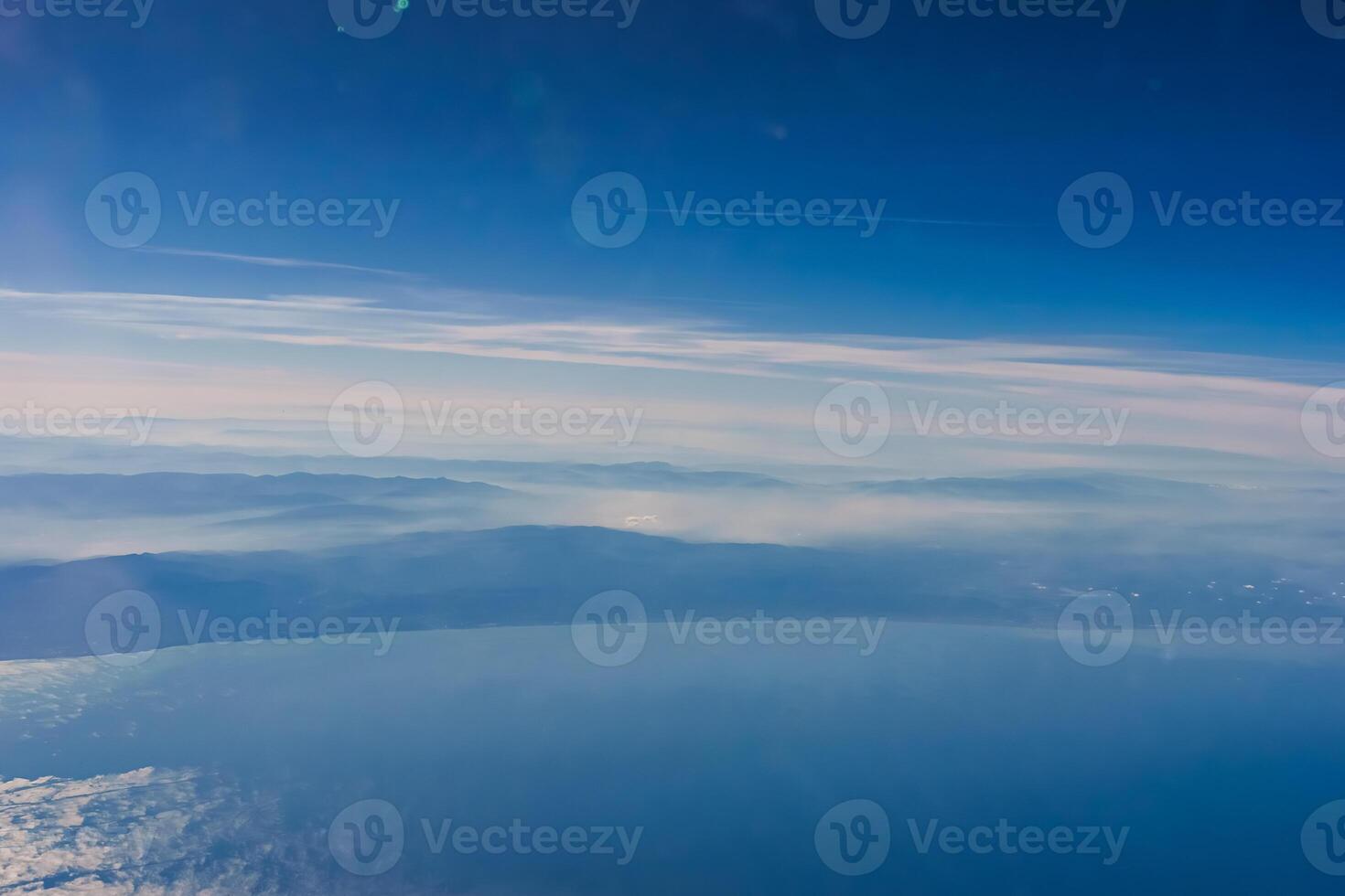 Aerial view from airplane window above green ground. View from the airplane window with beautiful clouds at sunrise. Earth and sky as seen through window of an airplane. photo