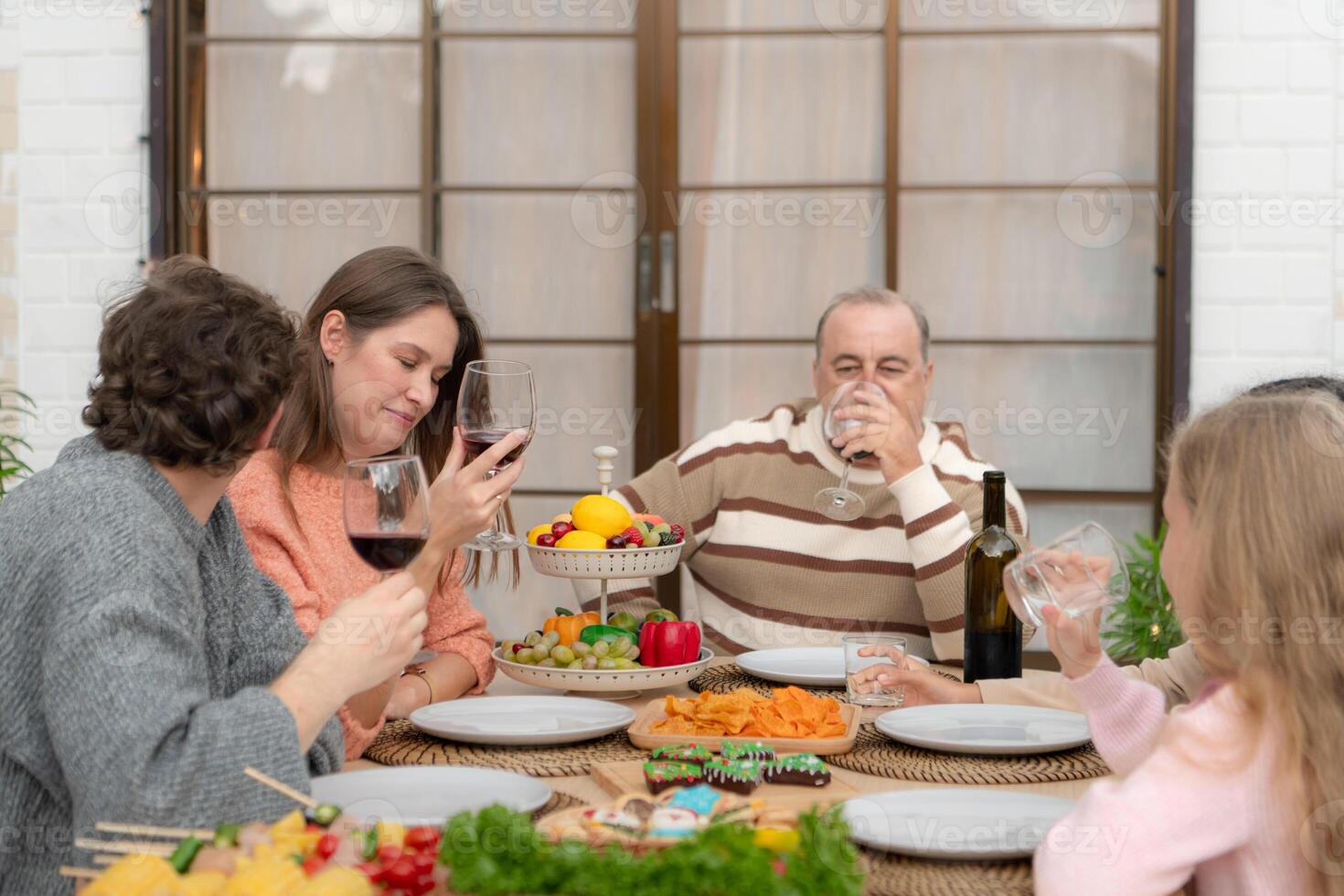 Grandfather, parents, and the teenage girls are all having dinner together at home photo