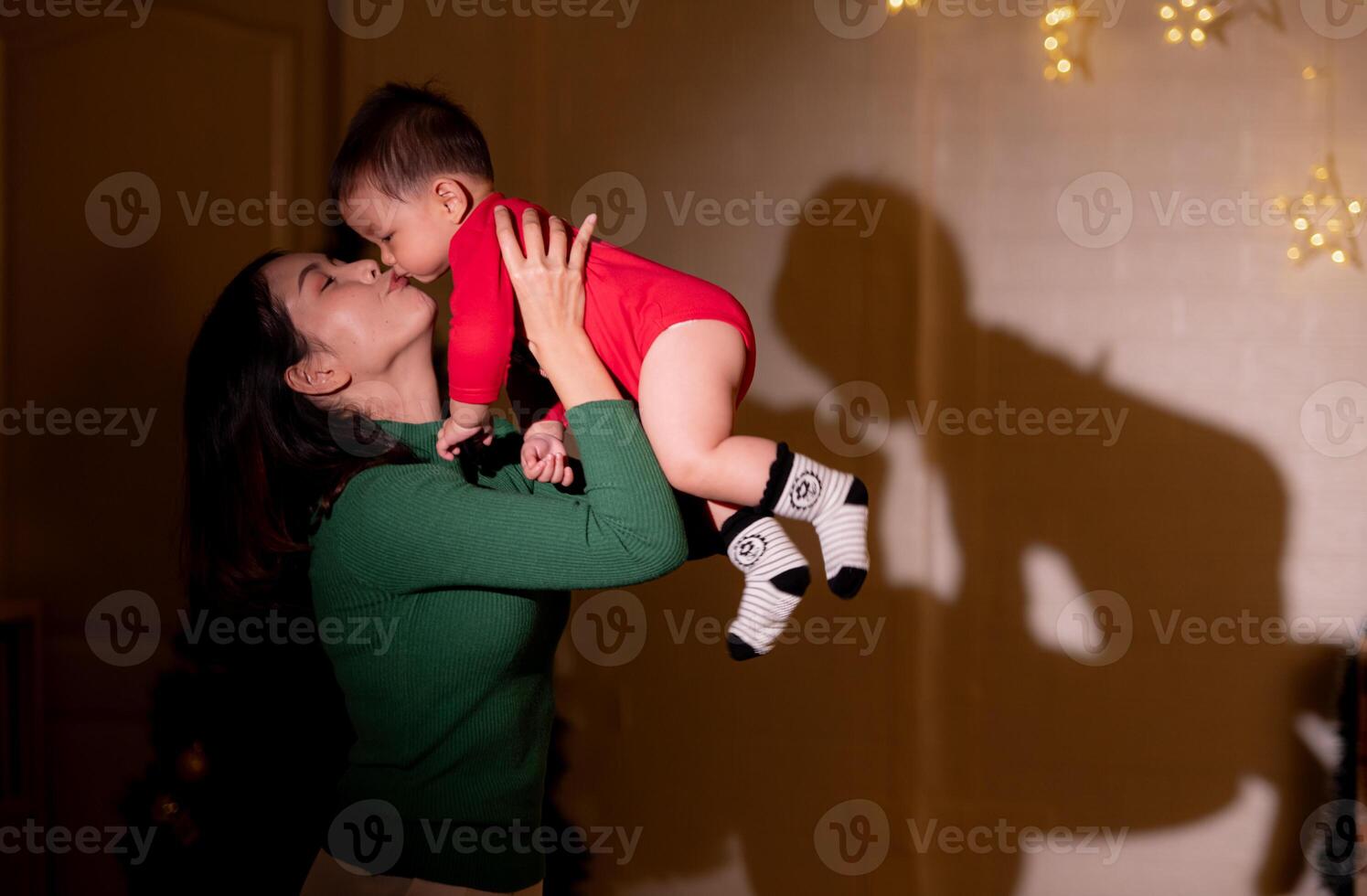 Mother and little boy in Christmas costume playing with shadows of lights on Christmas night photo