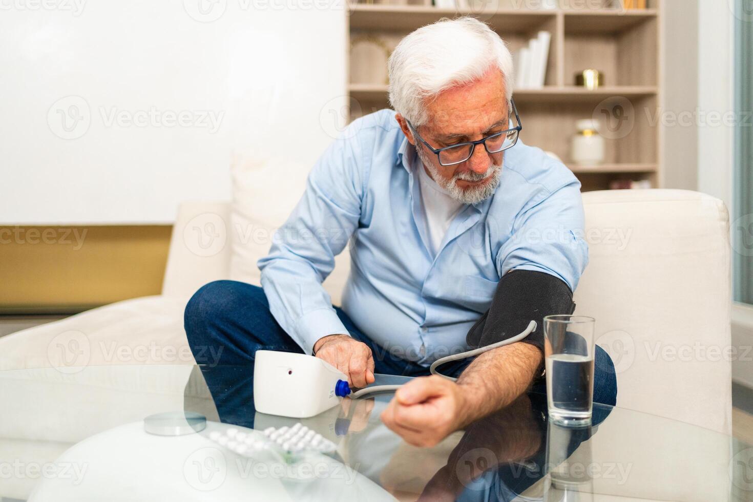 Hypertension problem in senior age. Old man measuring blood pressure with tonometer at home. Senior man have health problem making self checkup. Headache treatment of hypertension hypotension photo