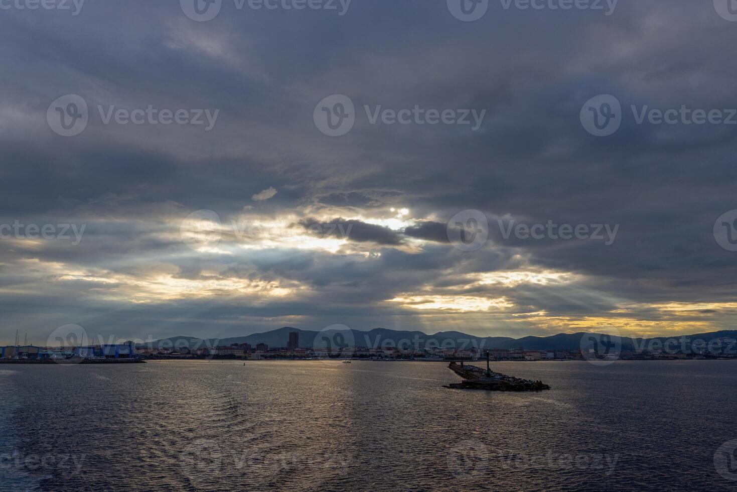 Morning scene at Livorno harbor with ferry at sunrise cloudy sky and sun rays reflecting on water photo