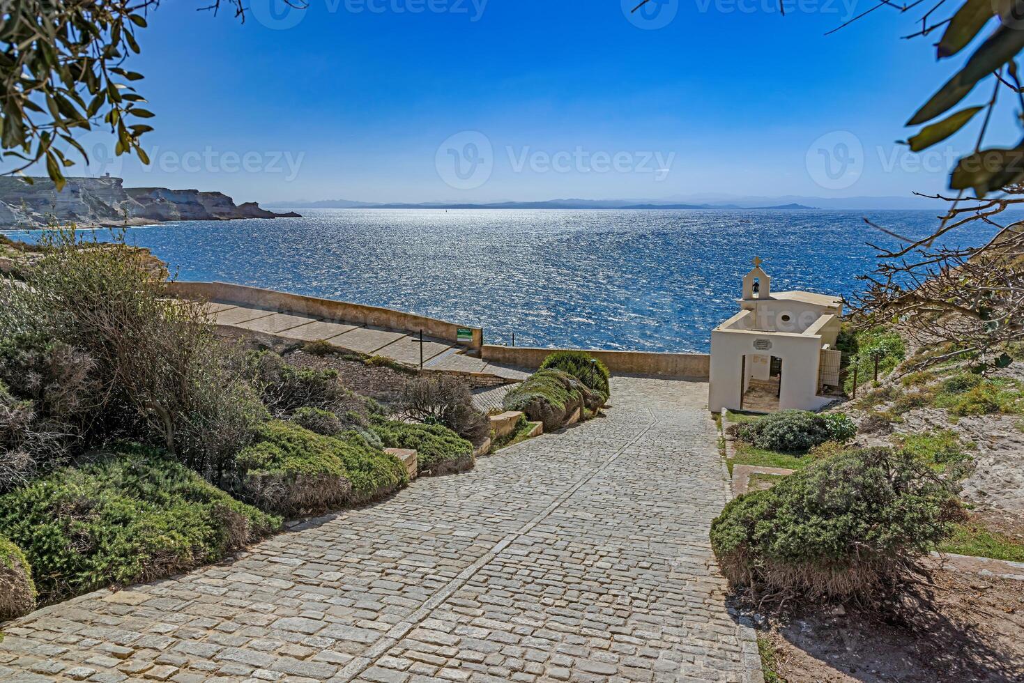 View from Bonifacio's cobbled path leading to the sea, with a small chapel and scenic Mediterranean horizon photo