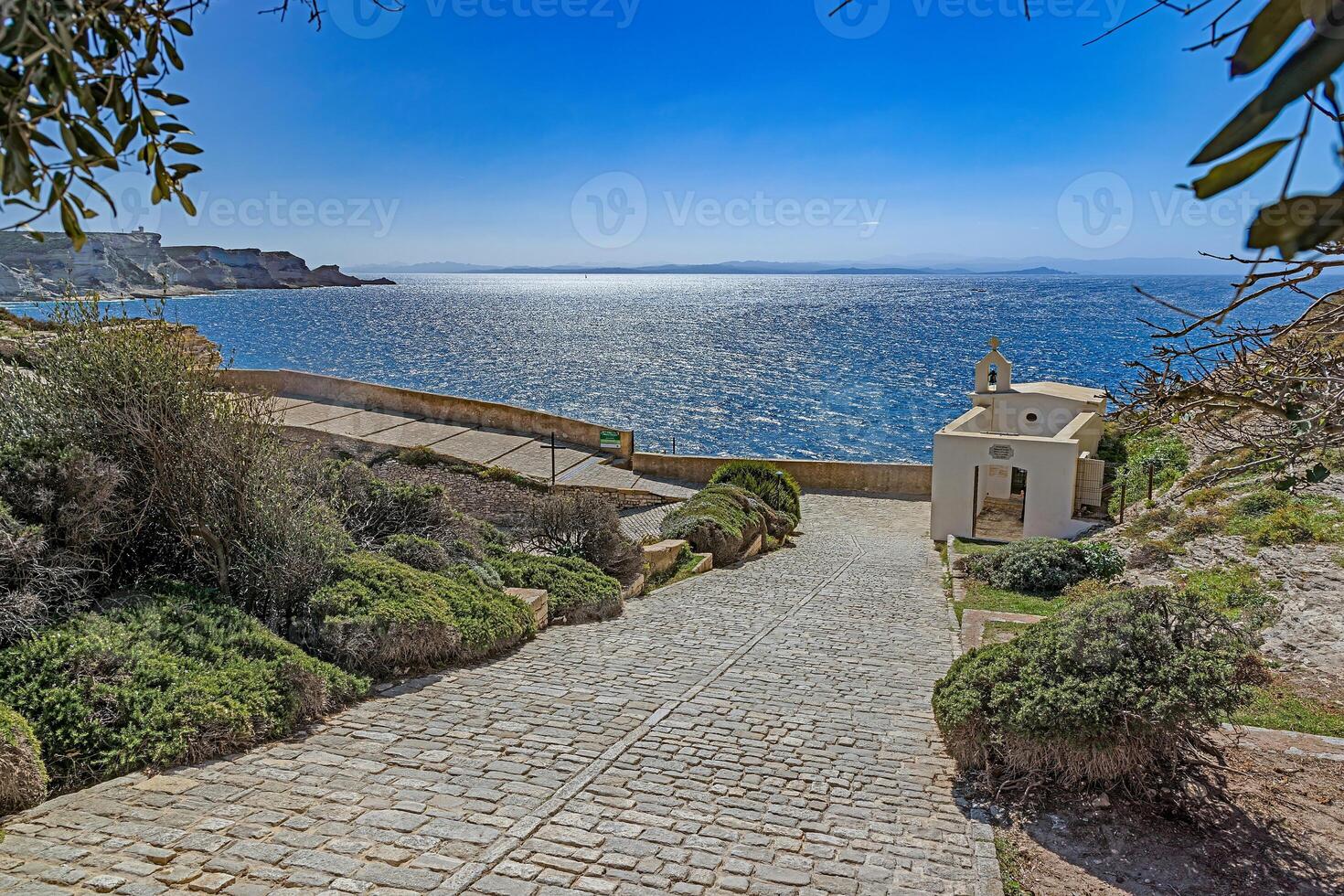 View from Bonifacio's cobbled path leading to the sea, with a small chapel and scenic Mediterranean horizon photo