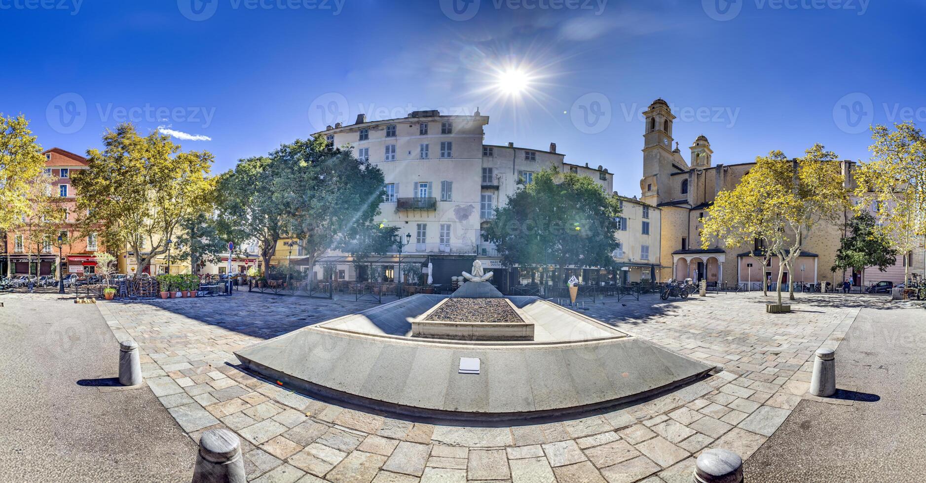 Historic square in Bastia's old town, Corsica, surrounded by buildings and trees under a blue sky photo