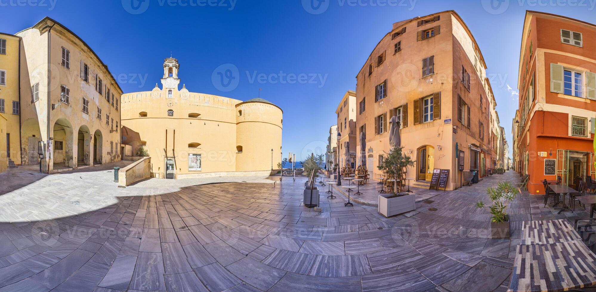 Historic square in Bastia's old town, Corsica, surrounded by buildings and trees under a blue sky photo