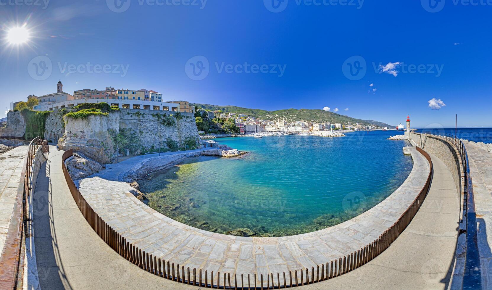 Scenic view of Bastia harbor wall and entrance with lighthouse under a bright blue sky photo