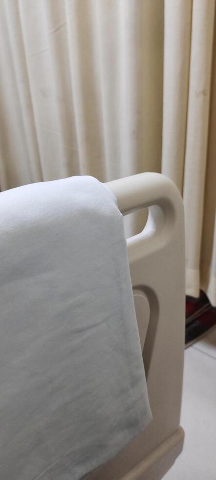A bed for hospital patients. There are supports made of plastic and aluminum on the edge of the bed, useful as protection so that the patient does not fall out of bed. photo