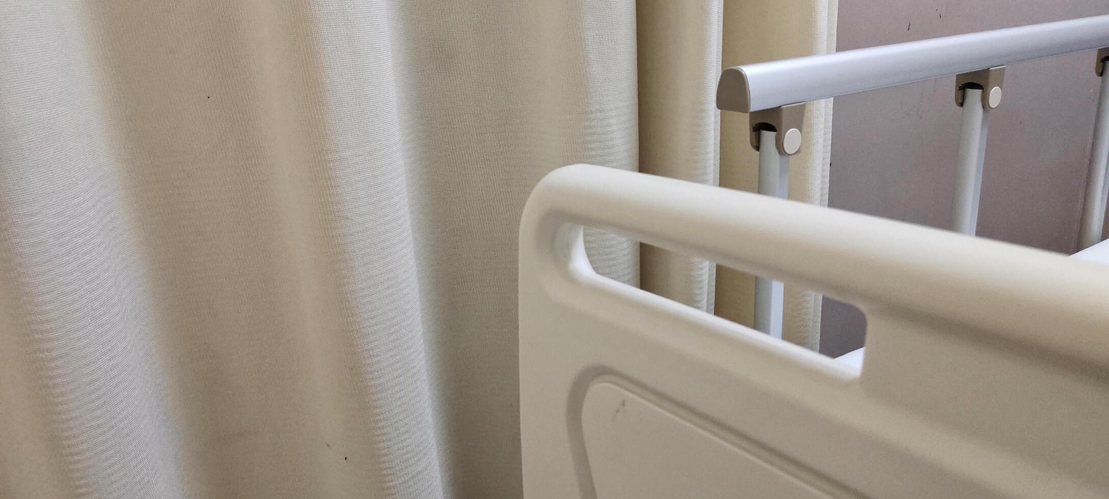 A bed for hospital patients. There are supports made of plastic and aluminum on the edge of the bed, useful as protection so that the patient does not fall out of bed. photo
