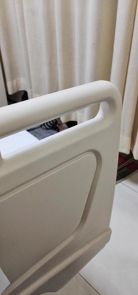 A bed for hospital patients. There are supports made of plastic and aluminum on the edge of the bed, useful as protection so that the patient does not fall out of bed. photo