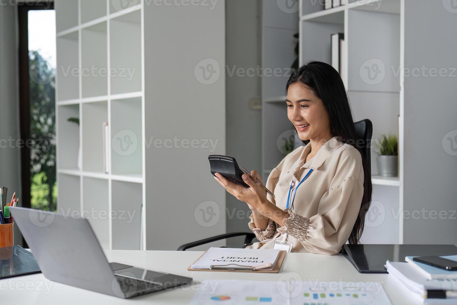 Female Accountant Analyzing Financial Management Documents at Modern Office Desk with Laptop and Calculator photo