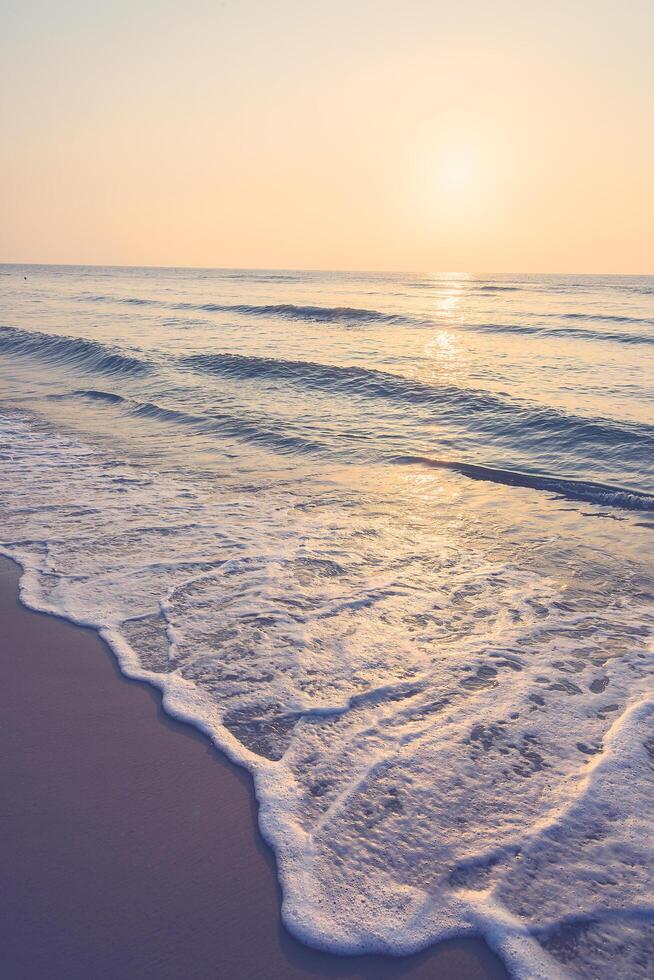 A beach with a wave at sunset photo