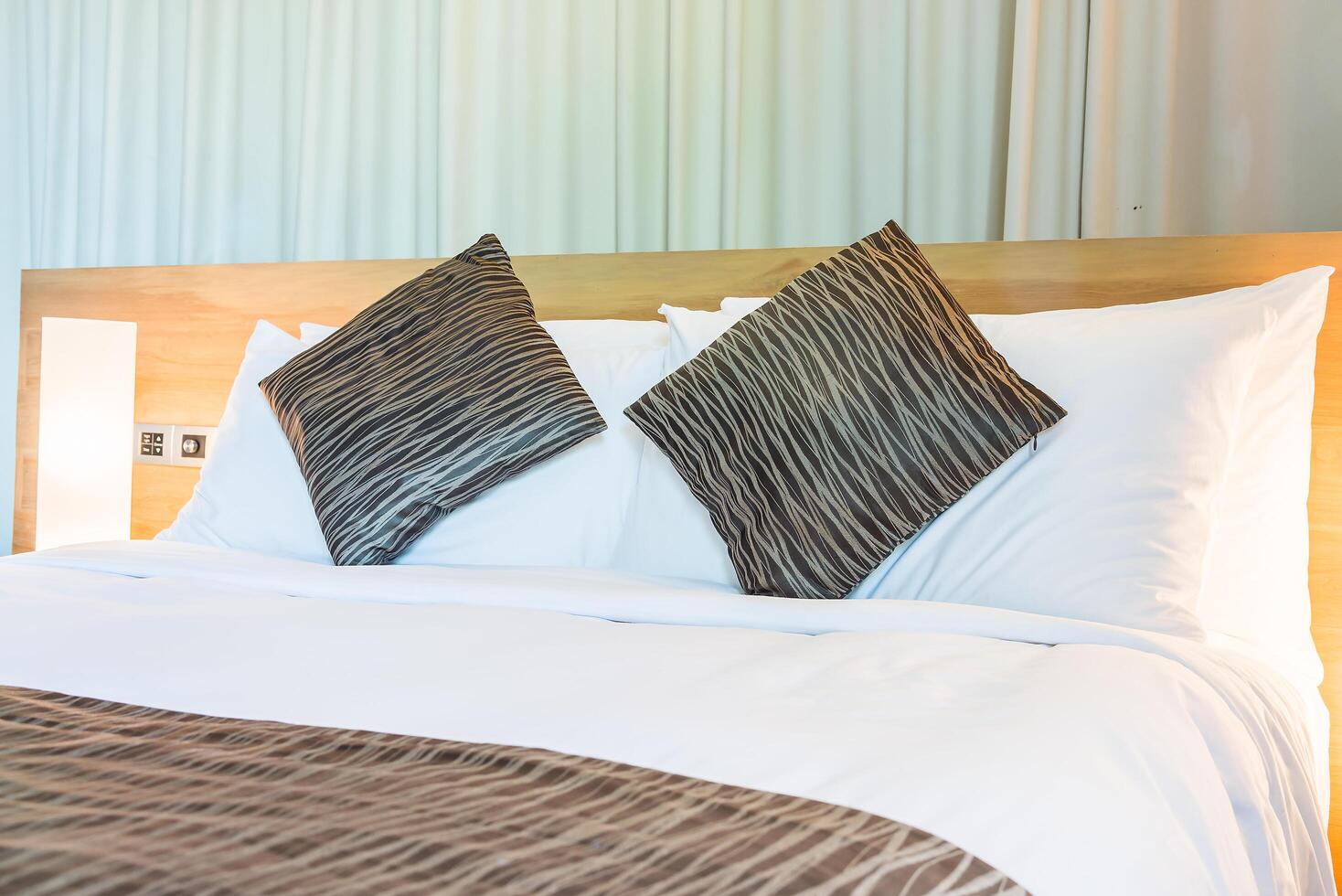 A bed with two pillows and a white blanket photo
