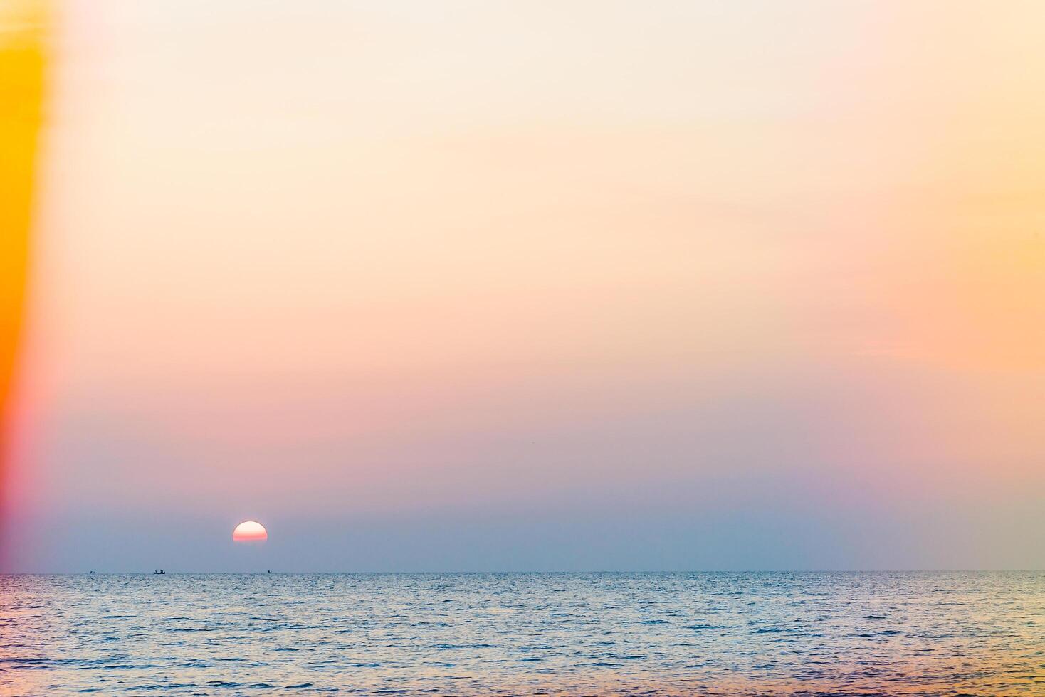 A sunset over the ocean with a colorful umbrella photo