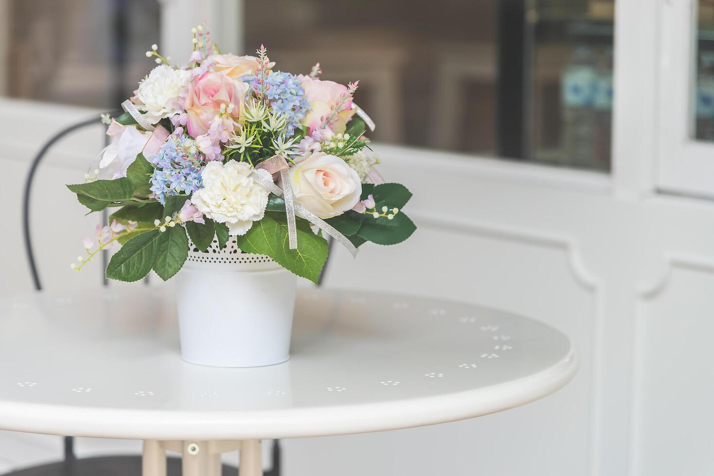 A white table with a white vase of flowers photo