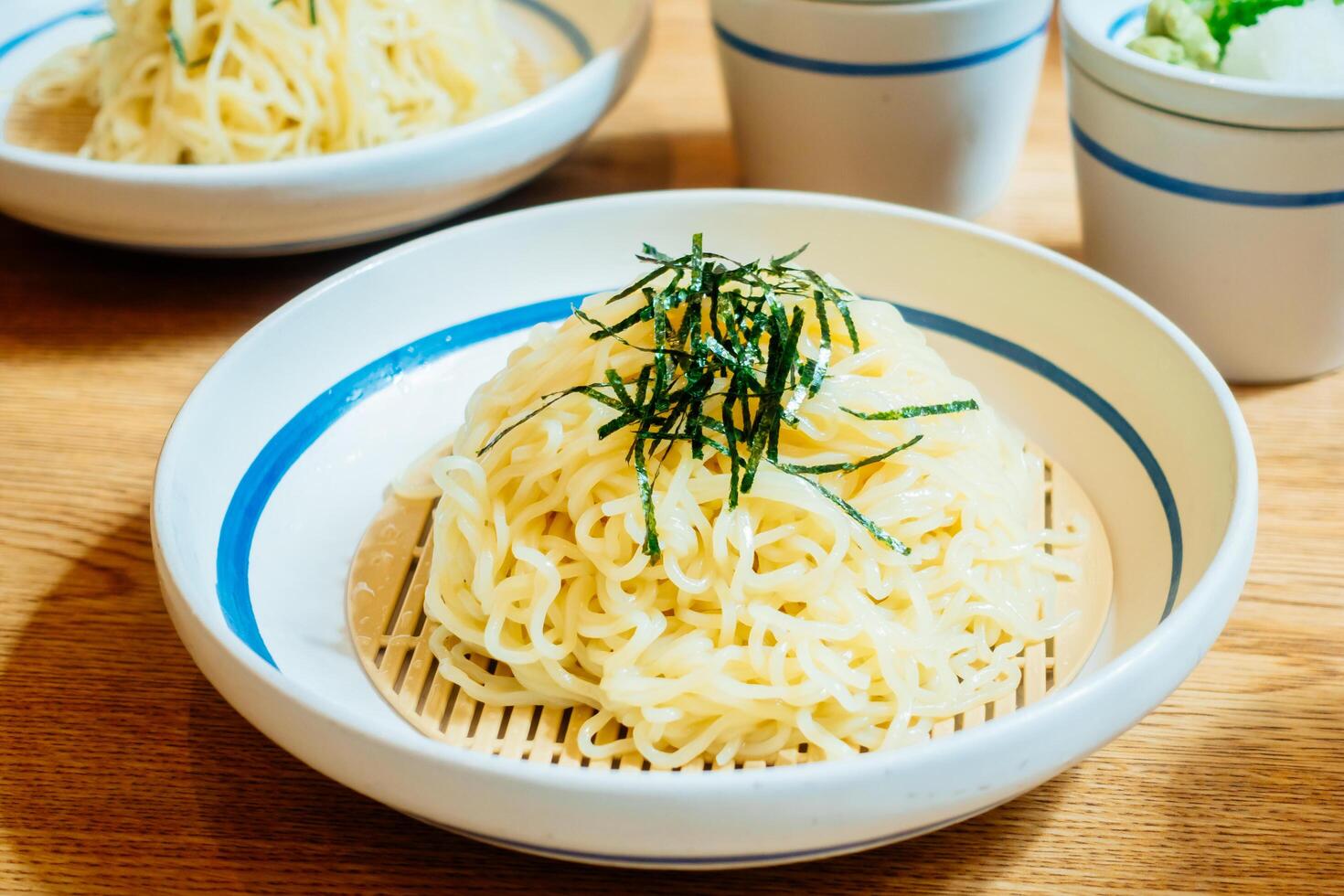 Two bowls of noodles sit on a table photo