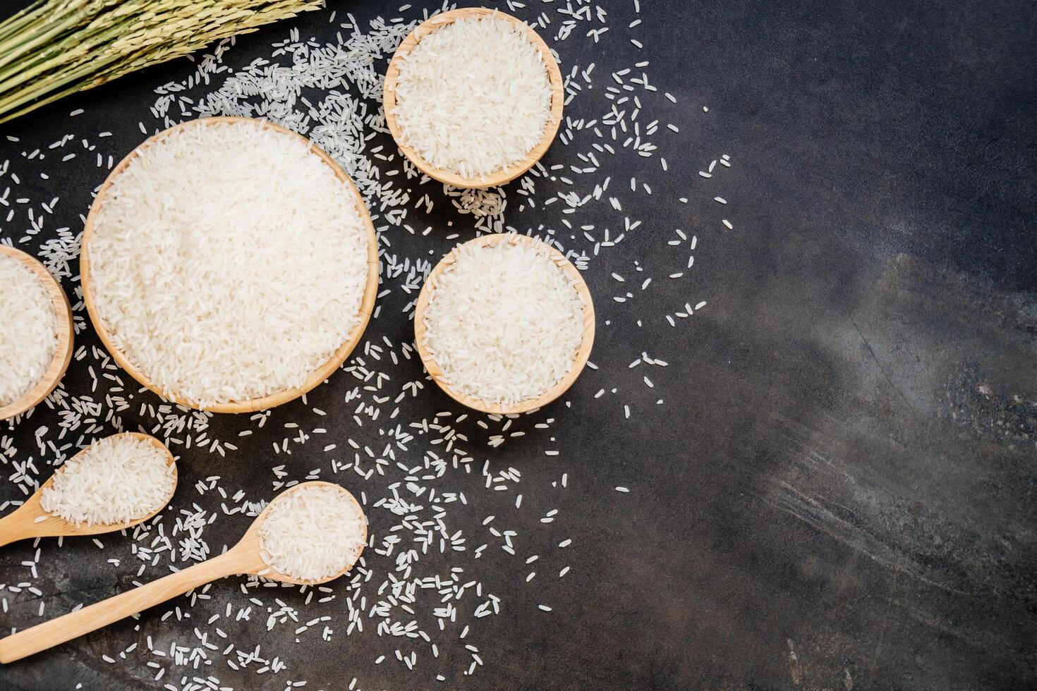 White rice in bowls and spoons on a black background photo