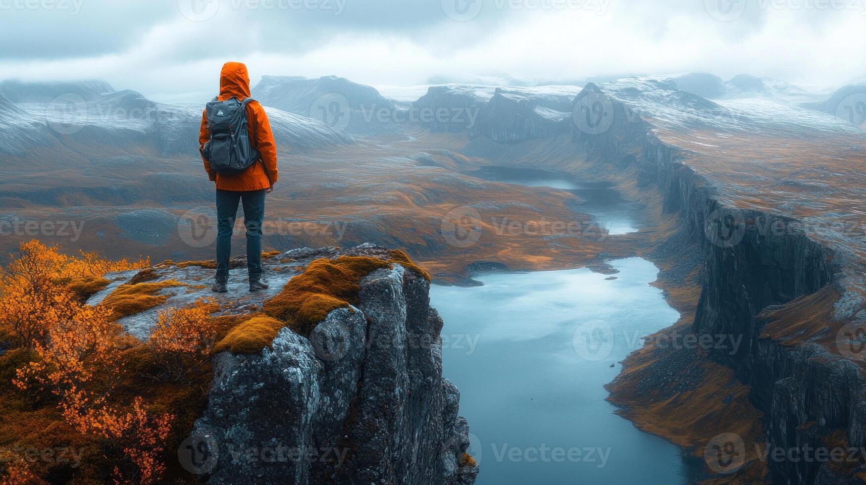 A person standing on top of a mountain overlooking a lake photo