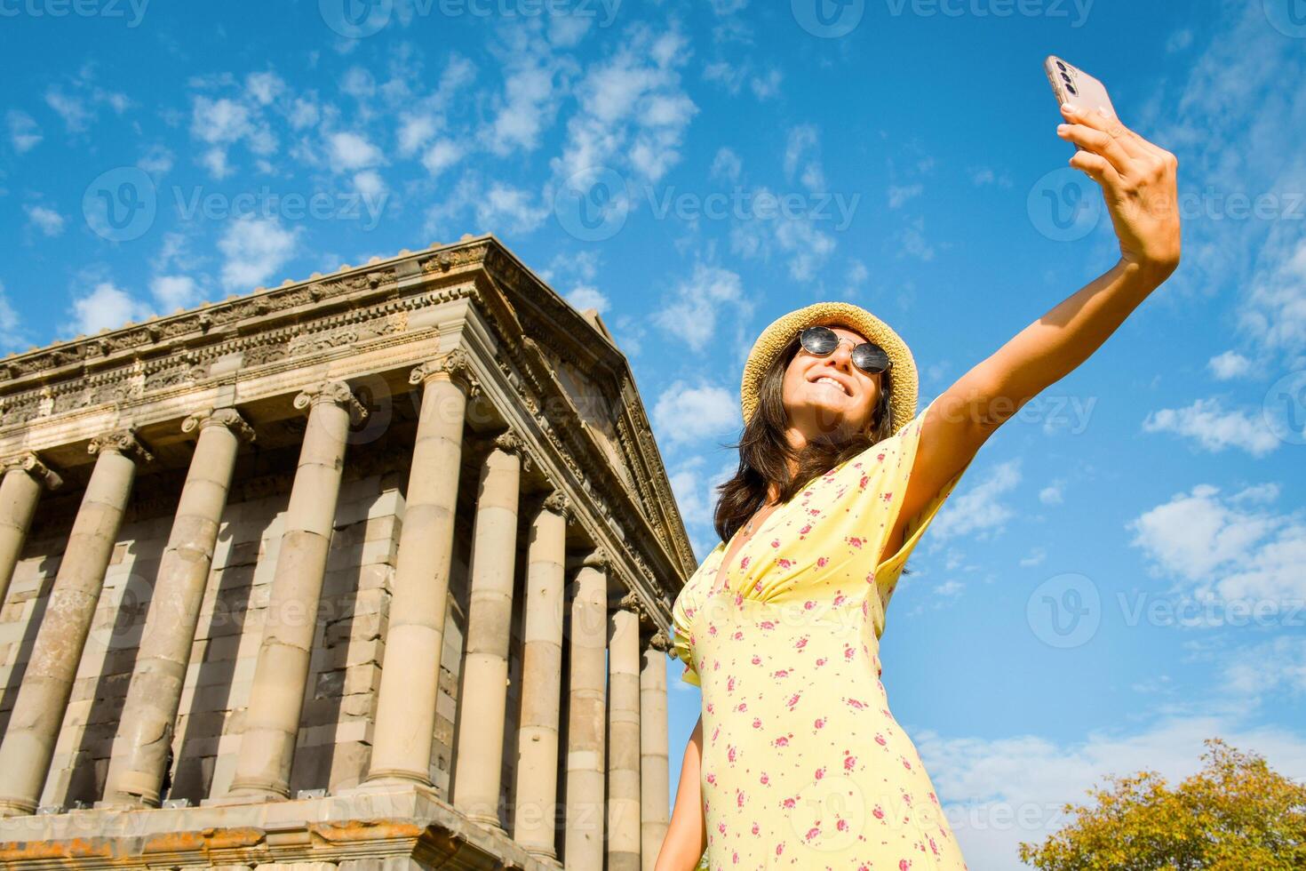 Pretty woman taking selfie in Armenia by Garni roman temple - Happy tourist having fun walking outside on summer vacation - Travel, holidays and European landmarks concept photo