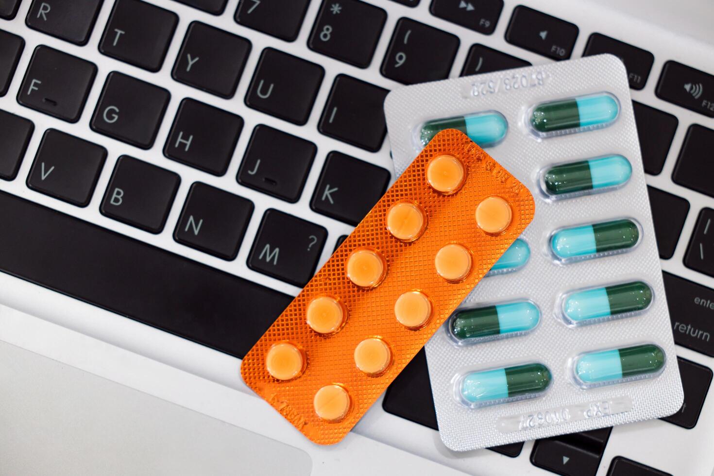 Medicine caps pills capsule pack on laptop computer keyboard, Office syndrome medical treatment from hard working with computer concept. photo