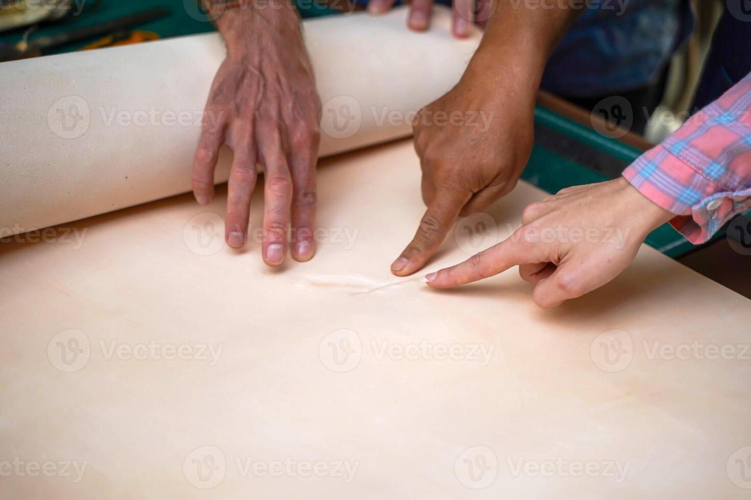 Closeup and crop hands of leather craftsman's team pointing at the flaw of the white leather. photo