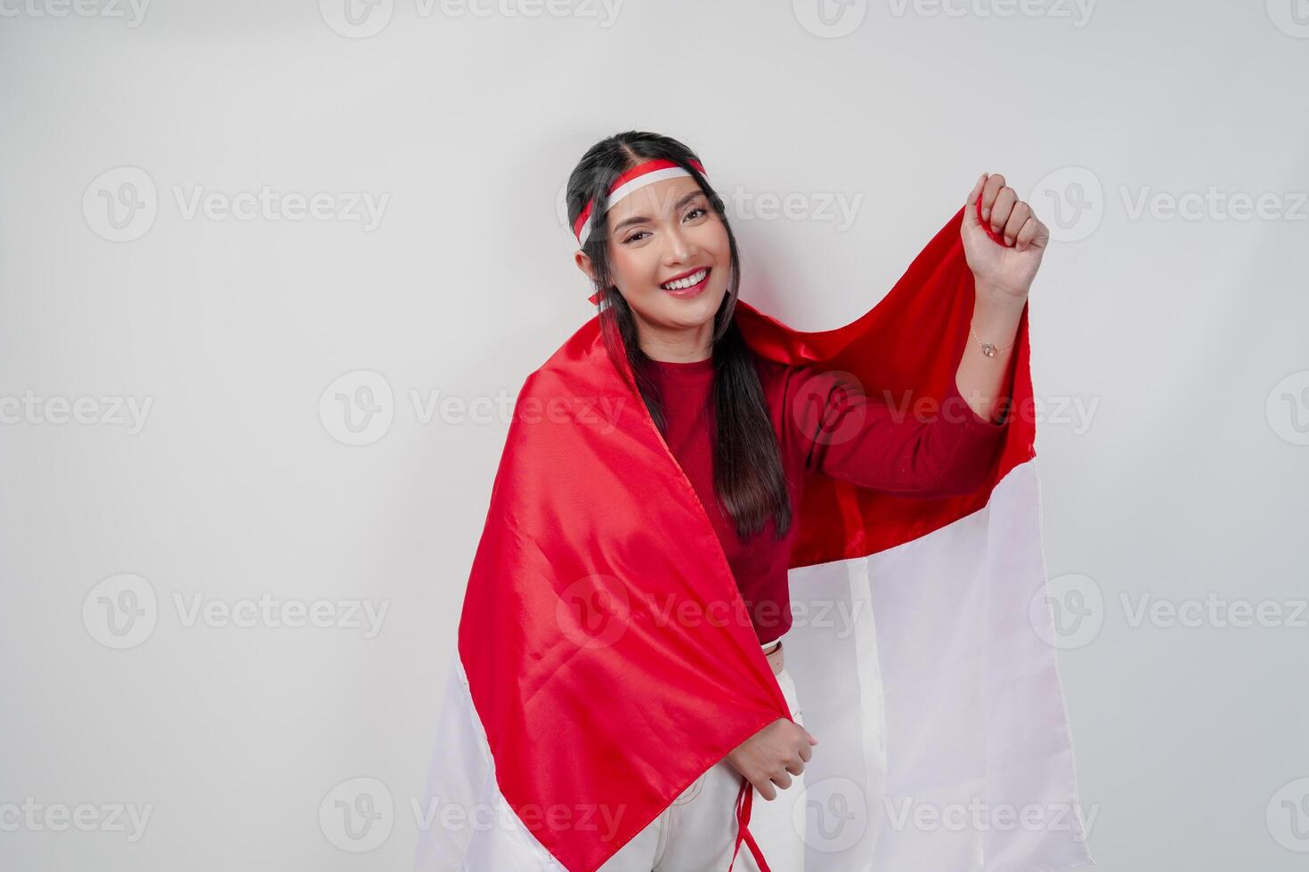 Confident Asian woman is covering herself with Indonesian flag and raising a fist. photo
