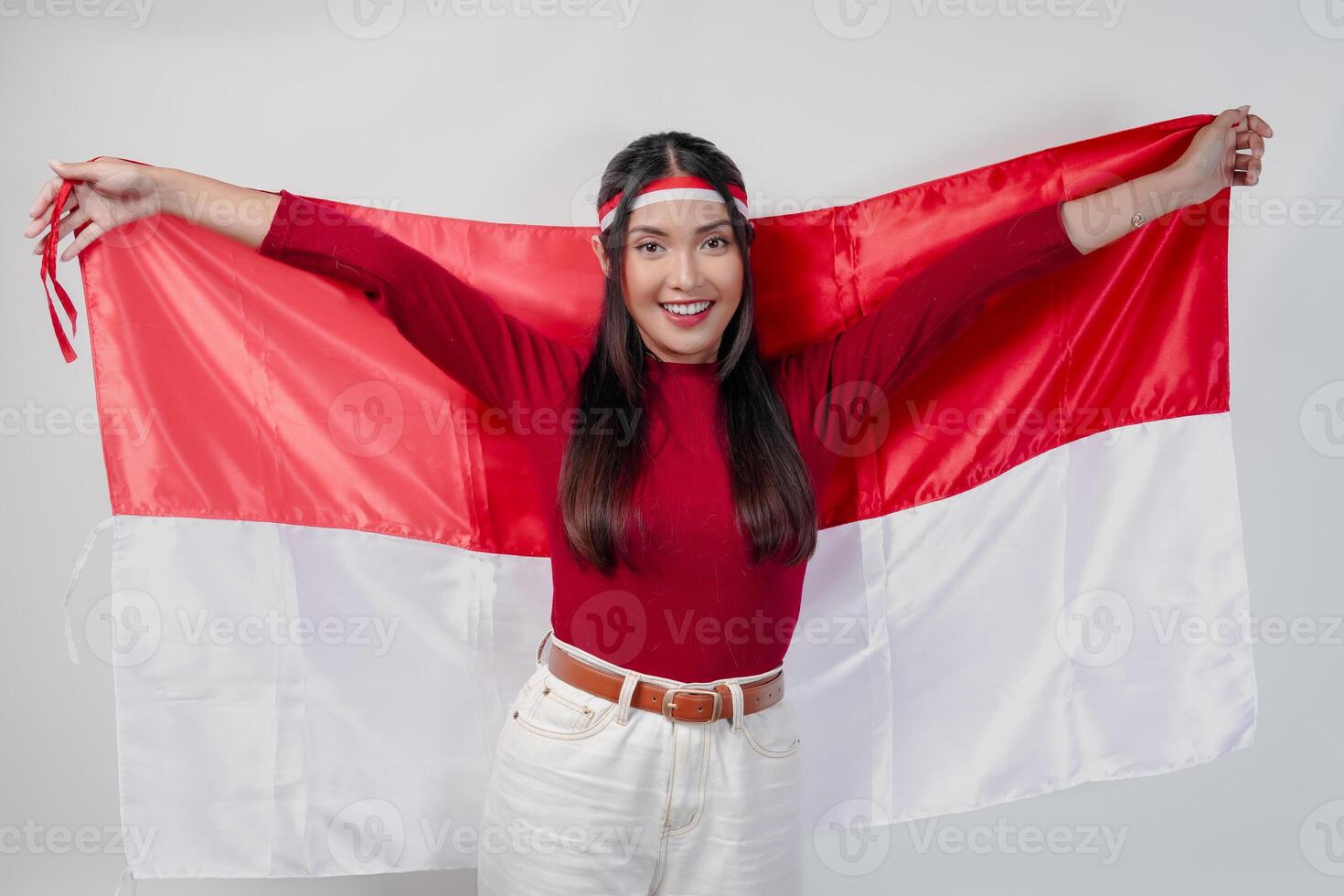 Joyful young Asian woman smiling and holding Indonesian flag behind. photo