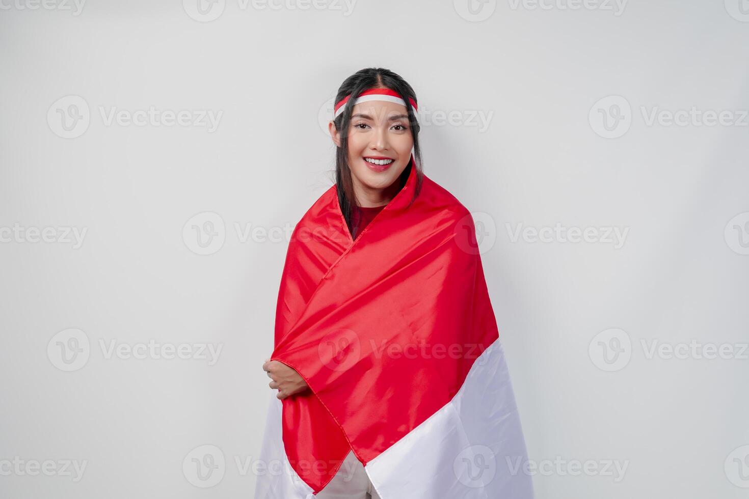 Smiling young Asian woman with Indonesian flag draped over her shoulders and posing for a picture. photo