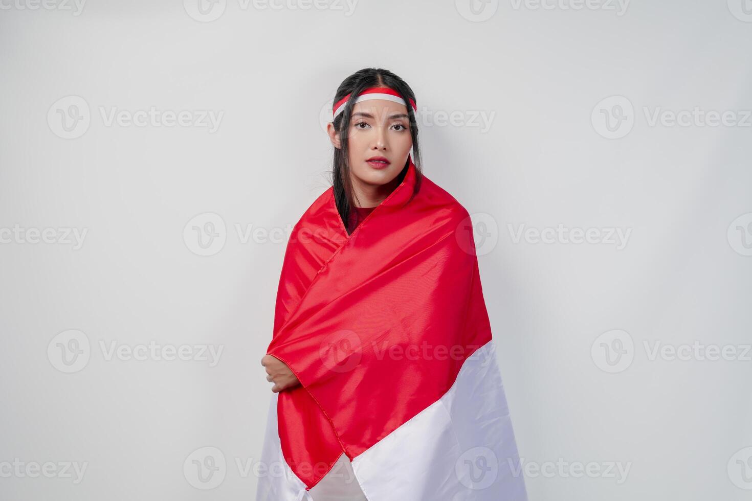Smiling young Asian woman with Indonesian flag draped over her shoulders and posing for a picture. photo