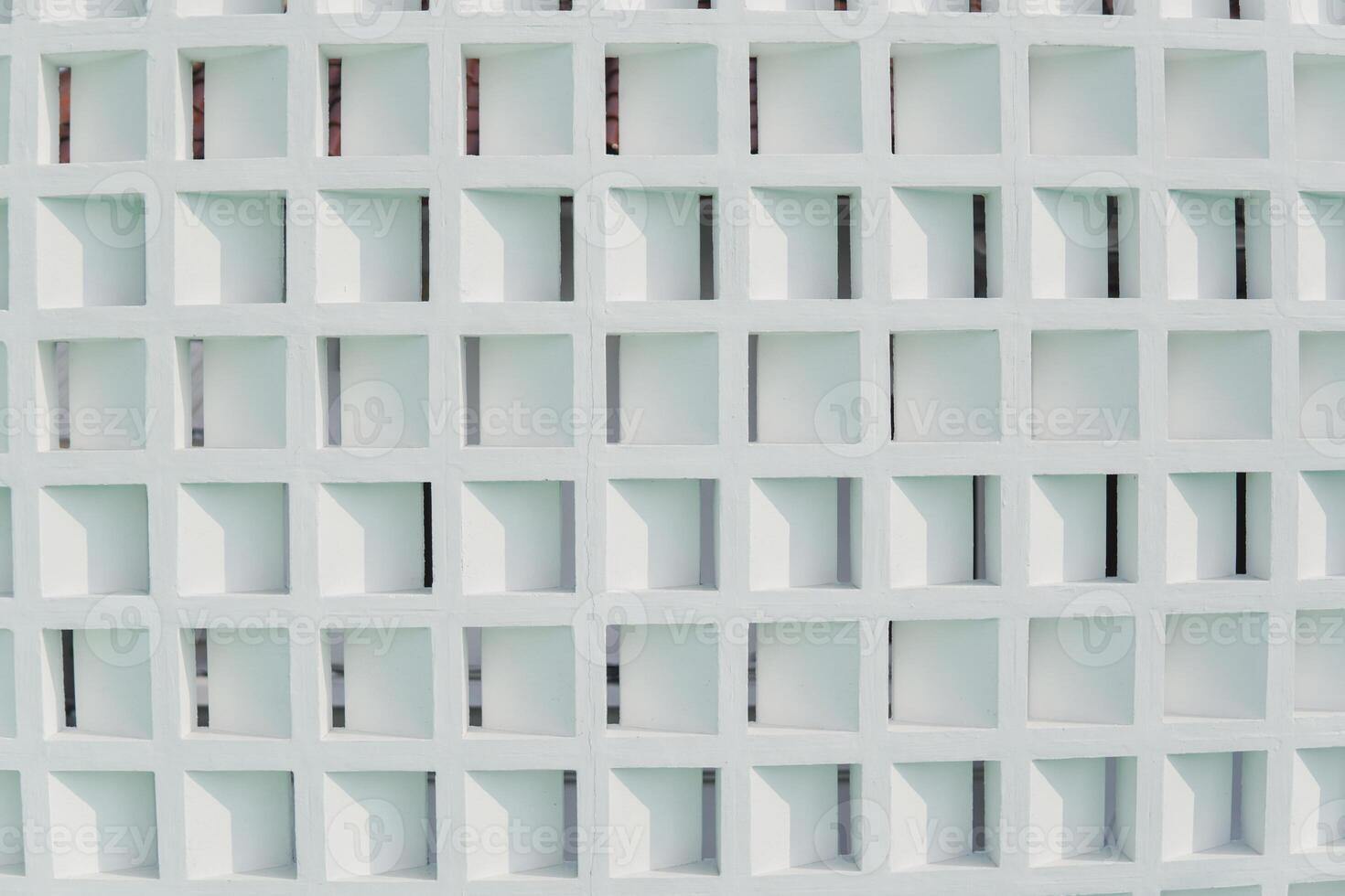 White wall made from concrete with a grid of same size squares and are evenly spaced apart. Pattern background concept. photo