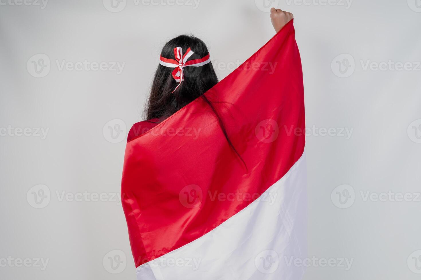 Back portrait of Indonesian young woman with country flag draped over her shoulders raising fist. photo