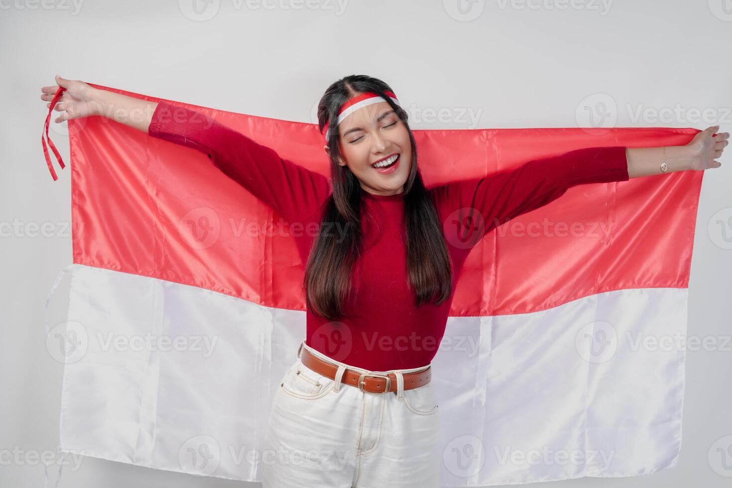 Joyful young Asian woman smiling and holding Indonesian flag behind. photo