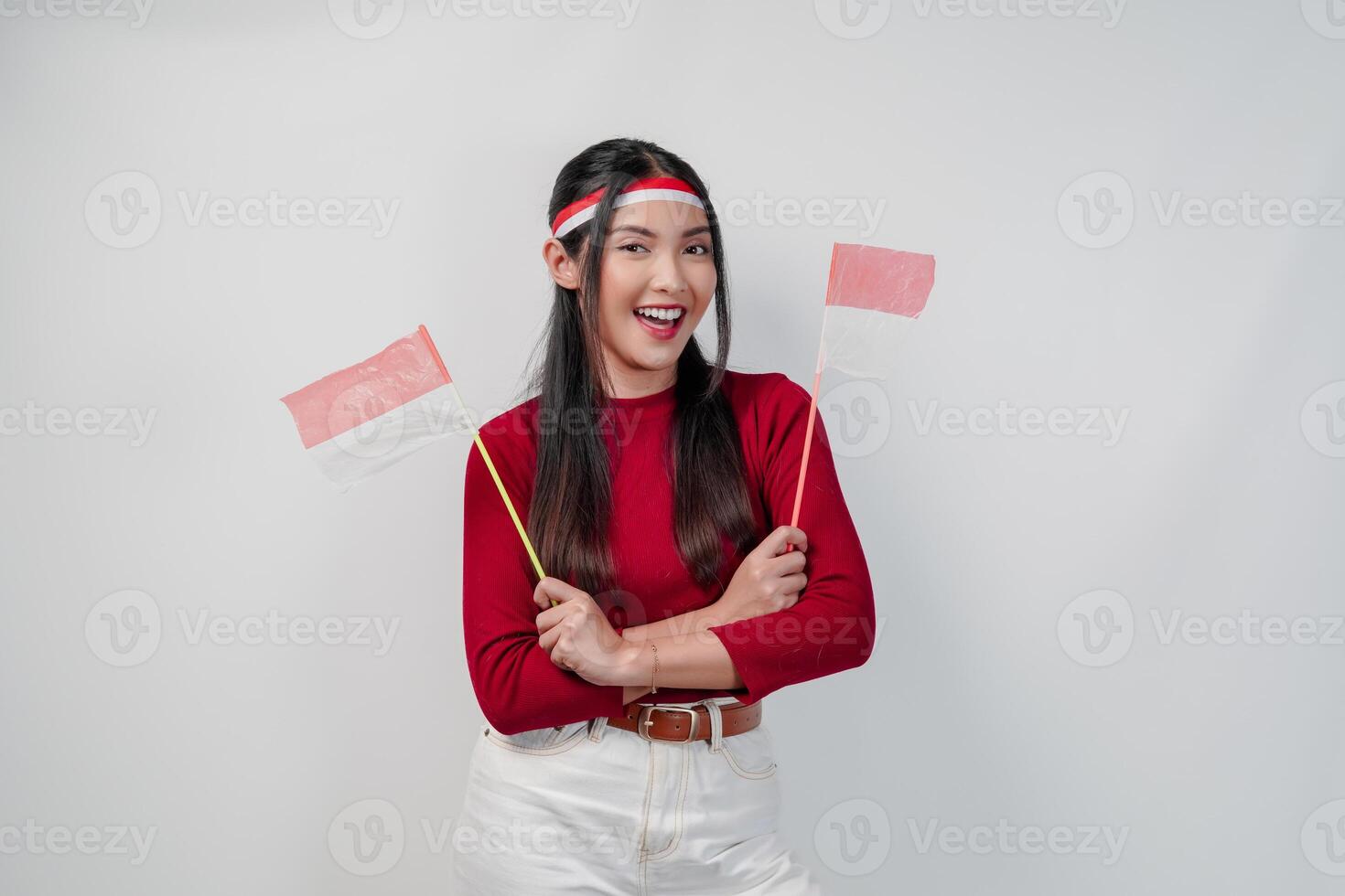 A happy young Asian woman is holding two mini Indonesian flags and smiling. photo