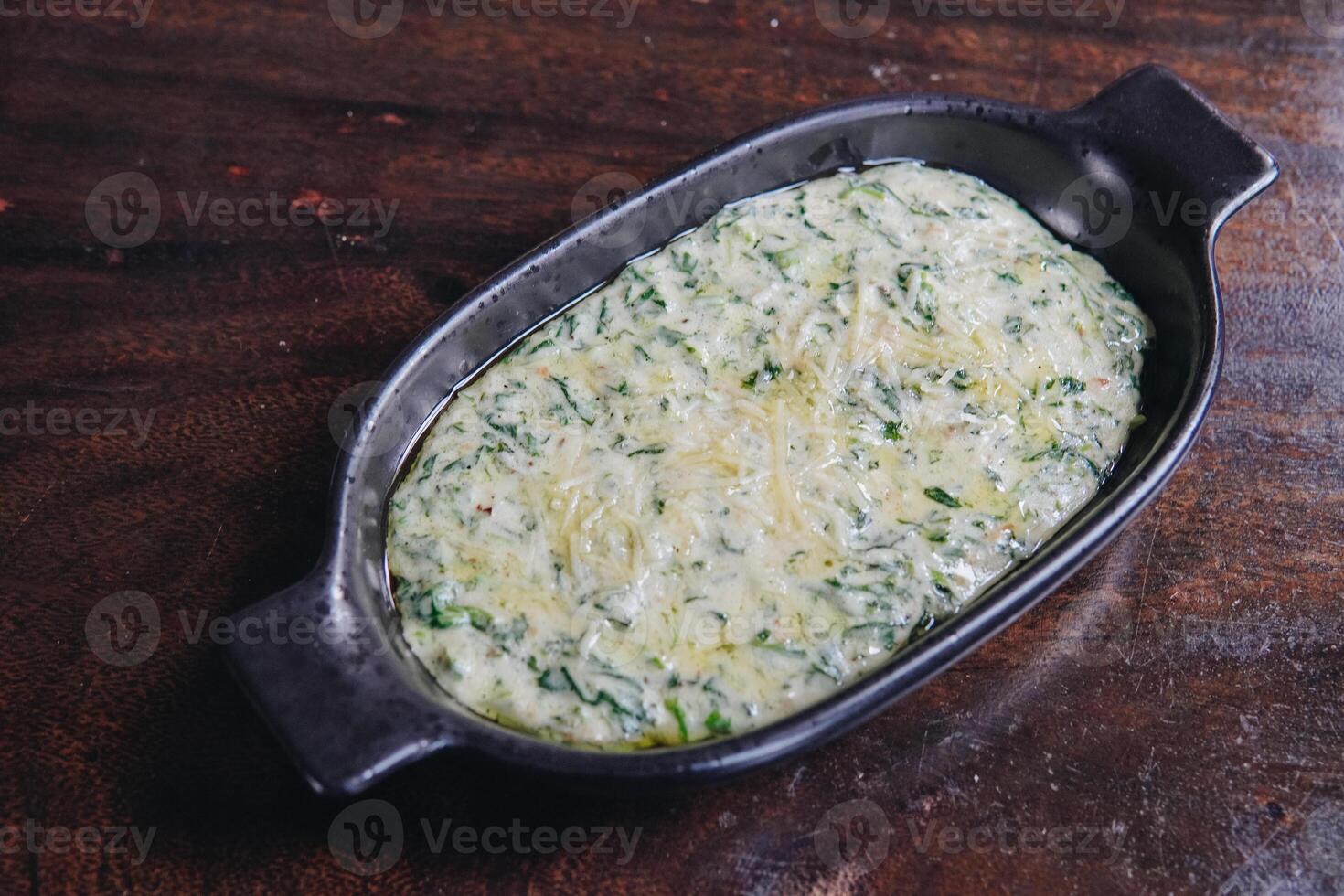 Delicious creamy spinach in a black bowl looks appetizing and inviting served on a wooden table. photo