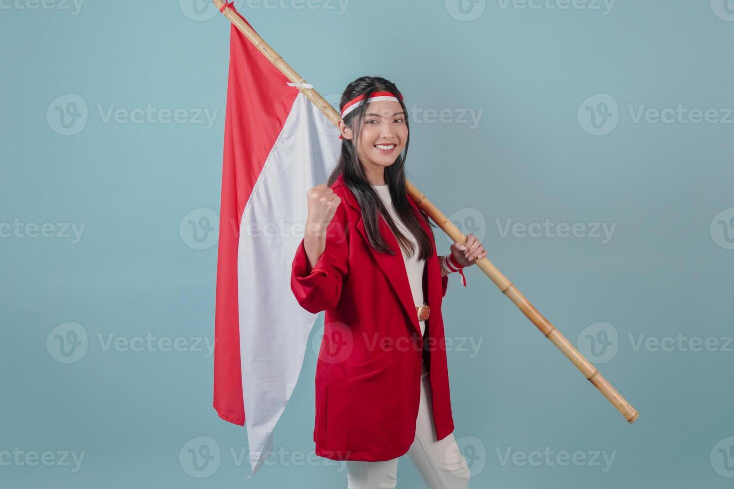 Smiling Indonesian woman holding a flag while raising fist gesture. photo