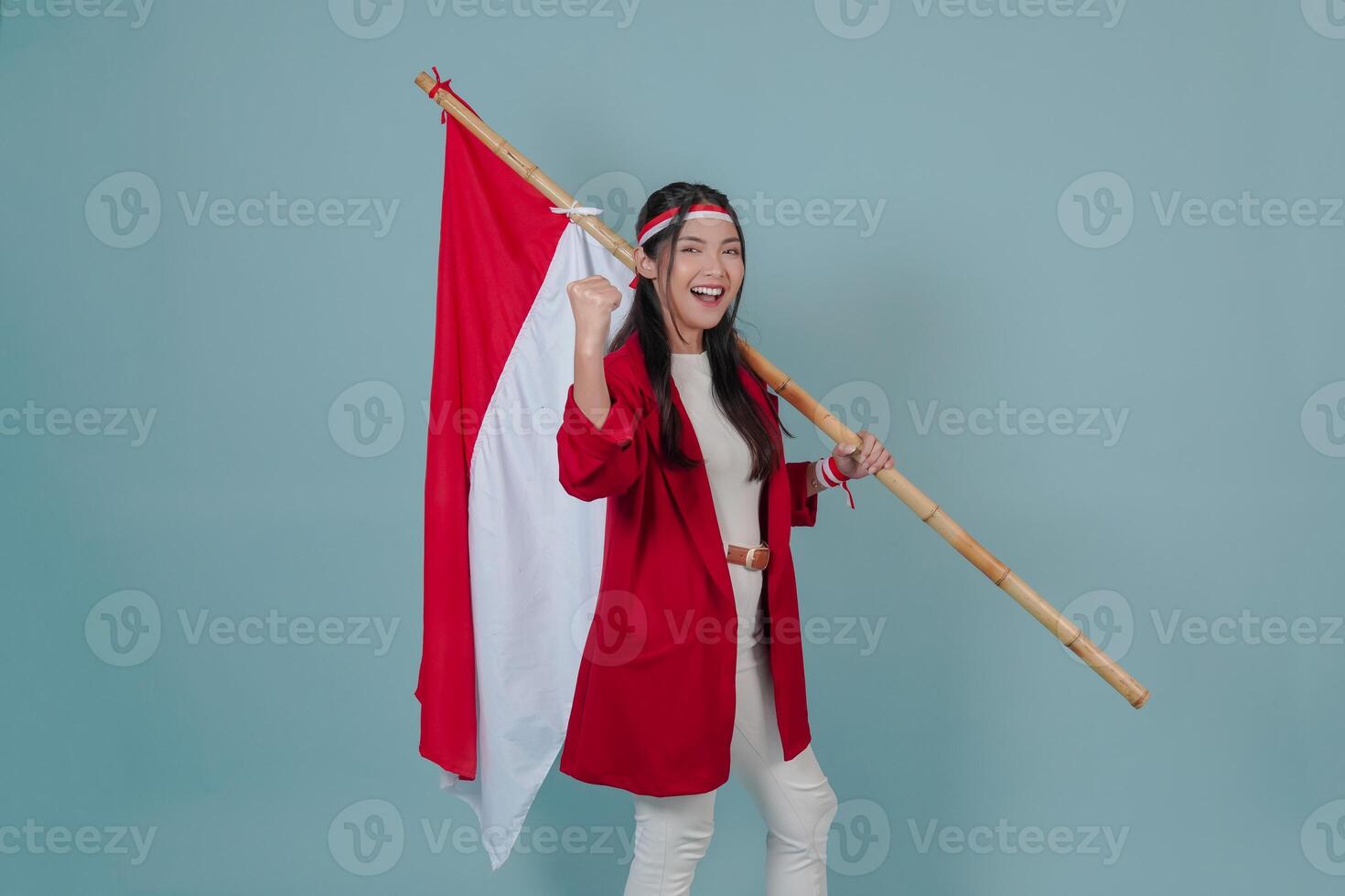 Smiling Indonesian woman holding a flag while raising fist gesture. photo
