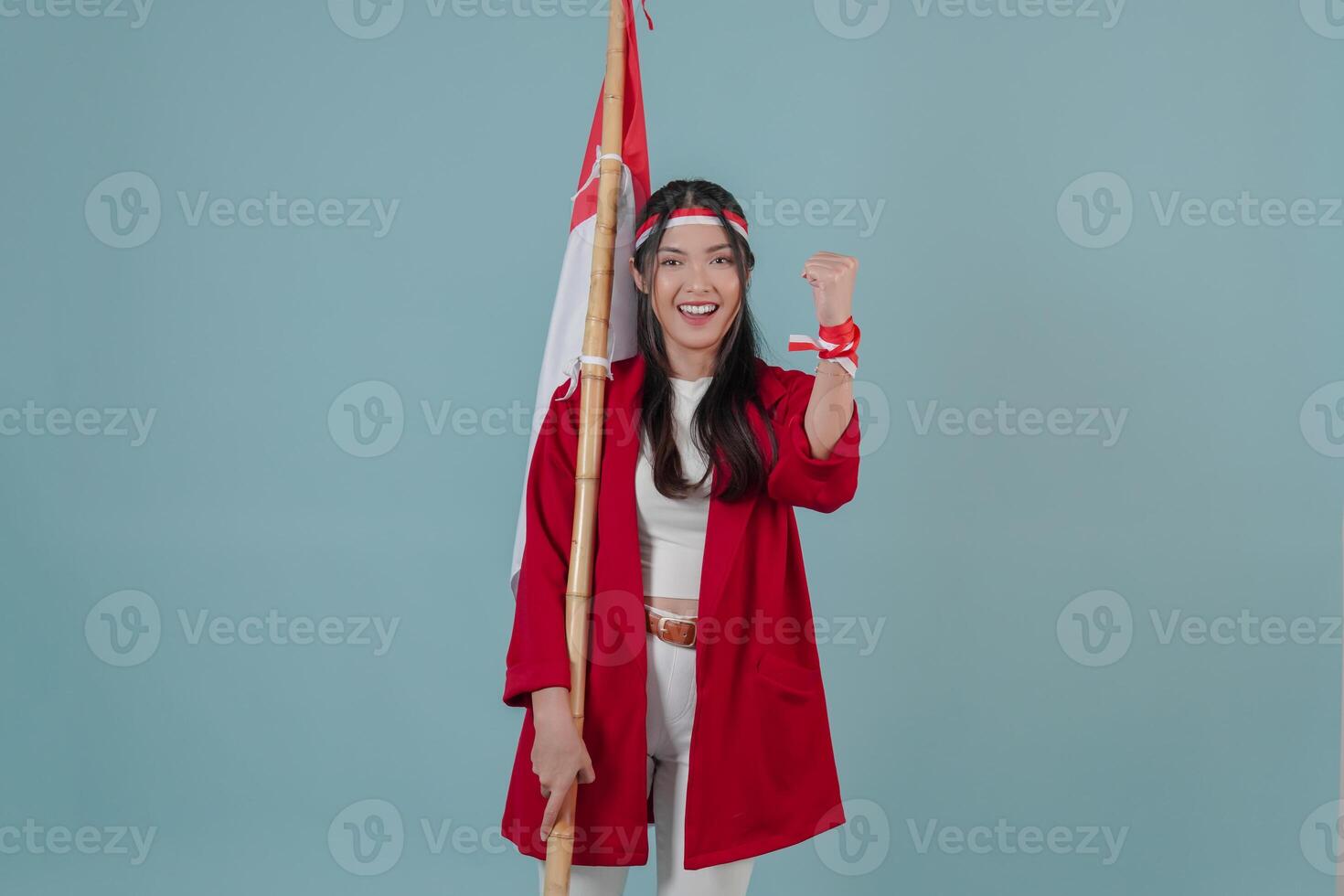 Cheerful Indonesian woman holding a flag while raising fist gesture. photo