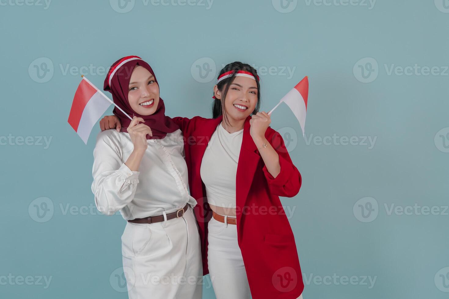 Two attractive Indonesian women holding mini country flag with a happy successful expression. photo