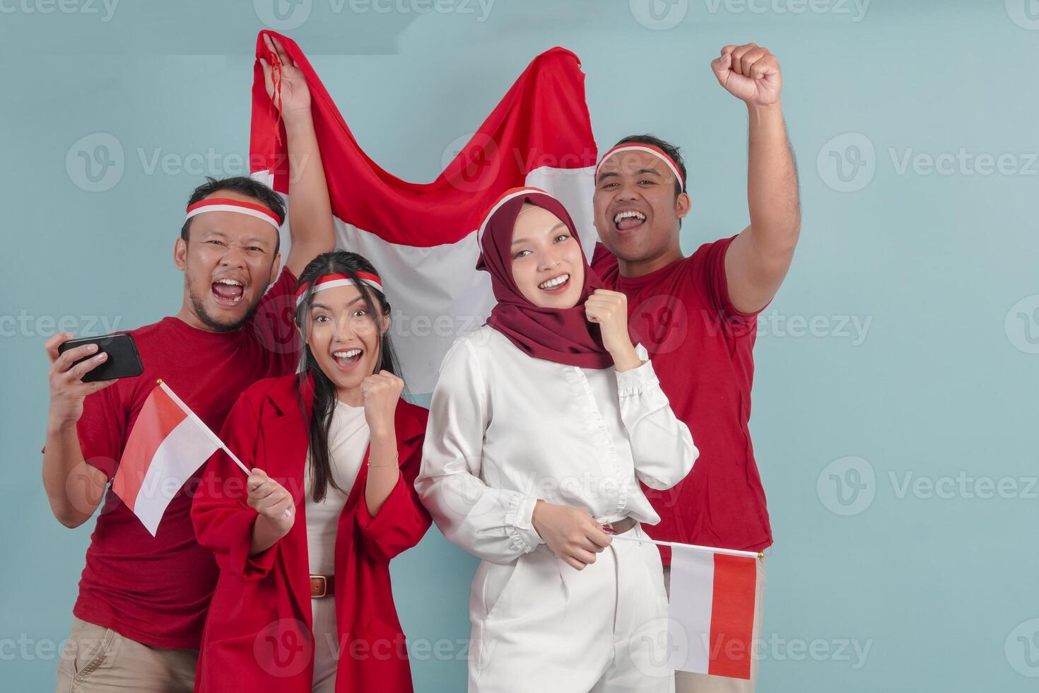 A group of Indonesian people are holding country flag while raising fist to celebrate something. photo