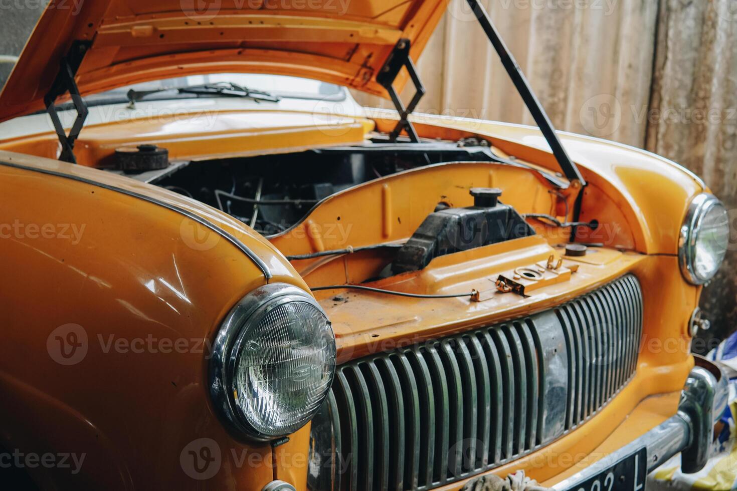 An old orange car with the hood up photo