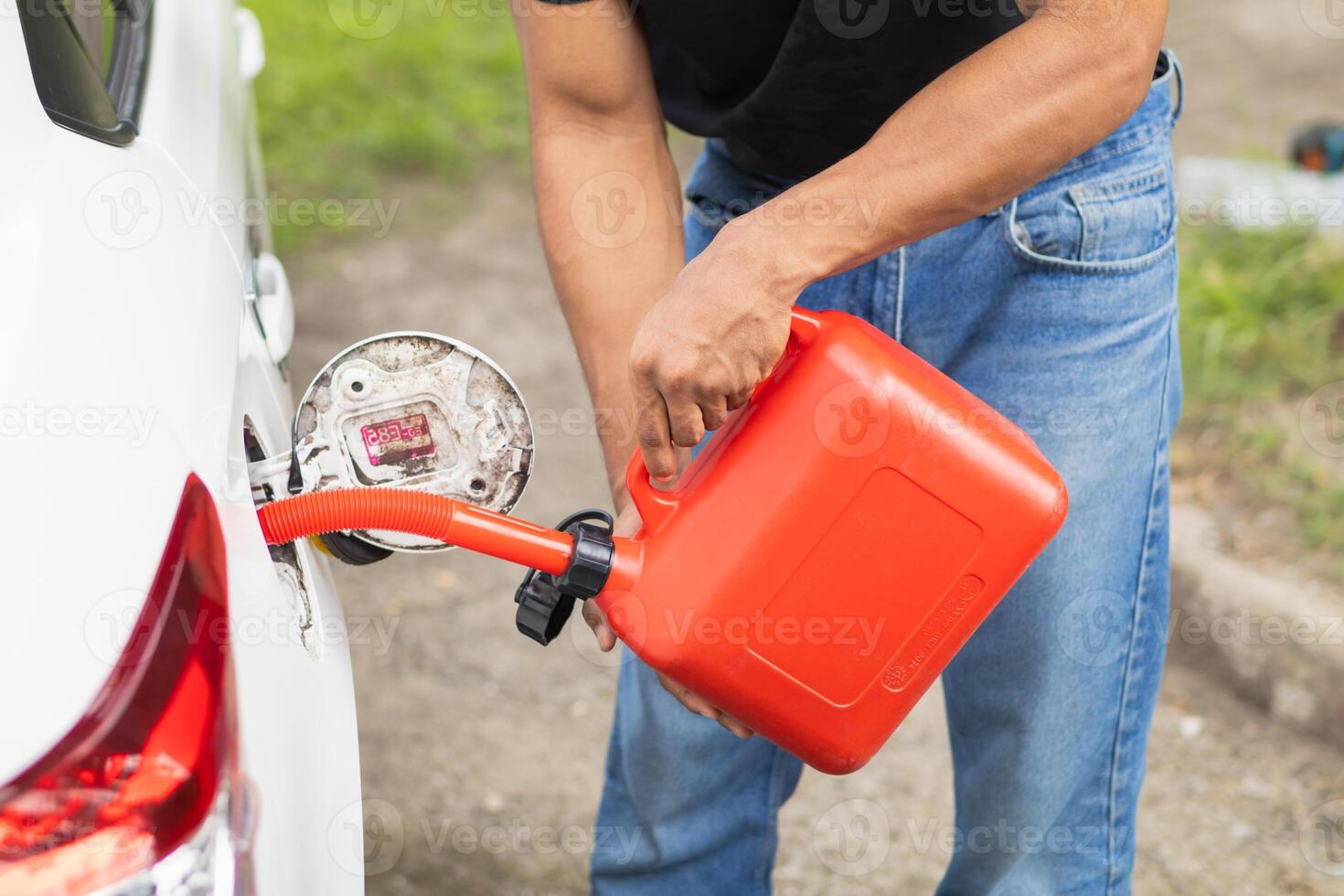 young man holds red gallon of gasoline which is reserve gasoline for emergency use when running out of fuel during trip or using reserve gasoline in red gallon to help people who run out of fuel. photo